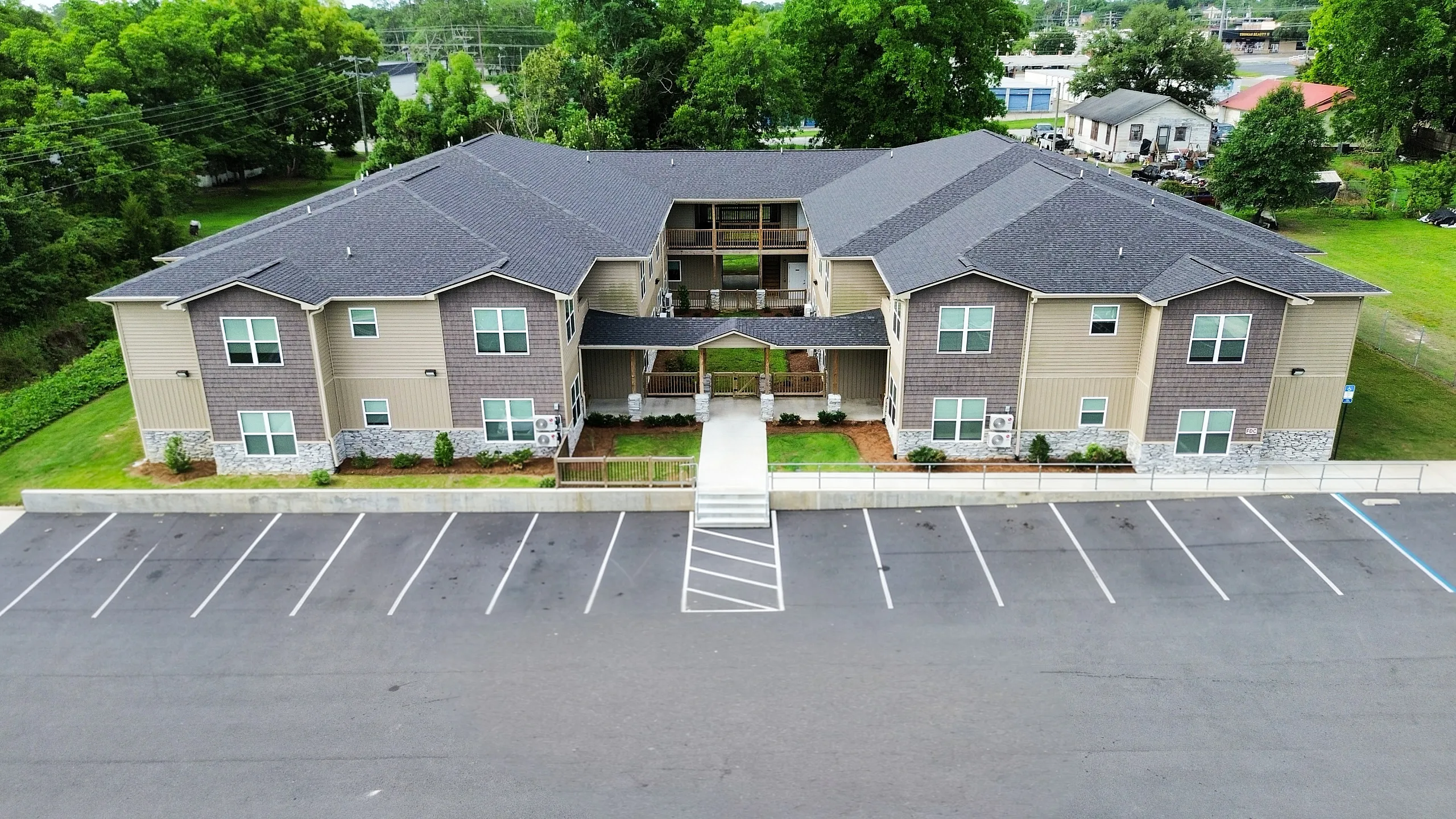 Modern two-story apartment complex with elegant design, surrounded by lush greenery and offering ample parking space.
