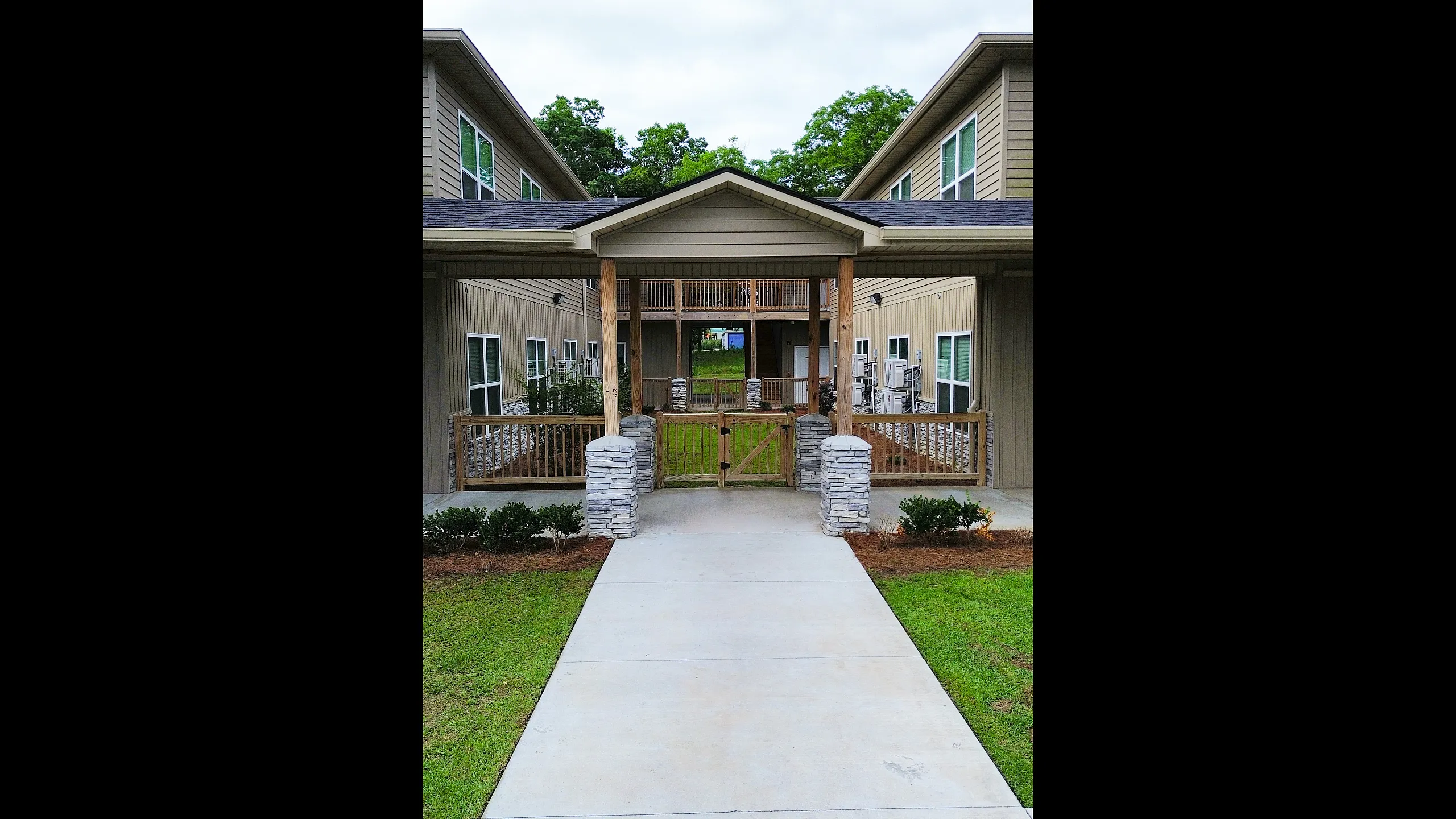 Inviting apartment entrance featuring rustic wooden accents and landscaped greenery, offering a warm and welcoming ambiance.