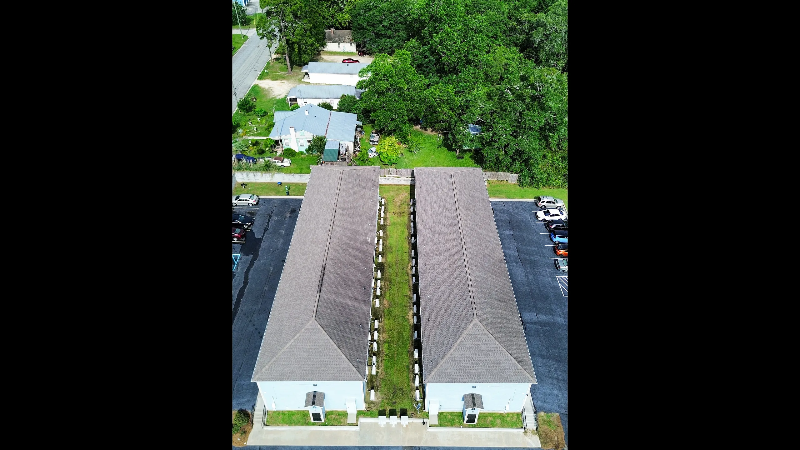 Aerial view showcasing a spacious apartment complex with dual buildings and lush greenery, offering a serene living environment and ample parking.