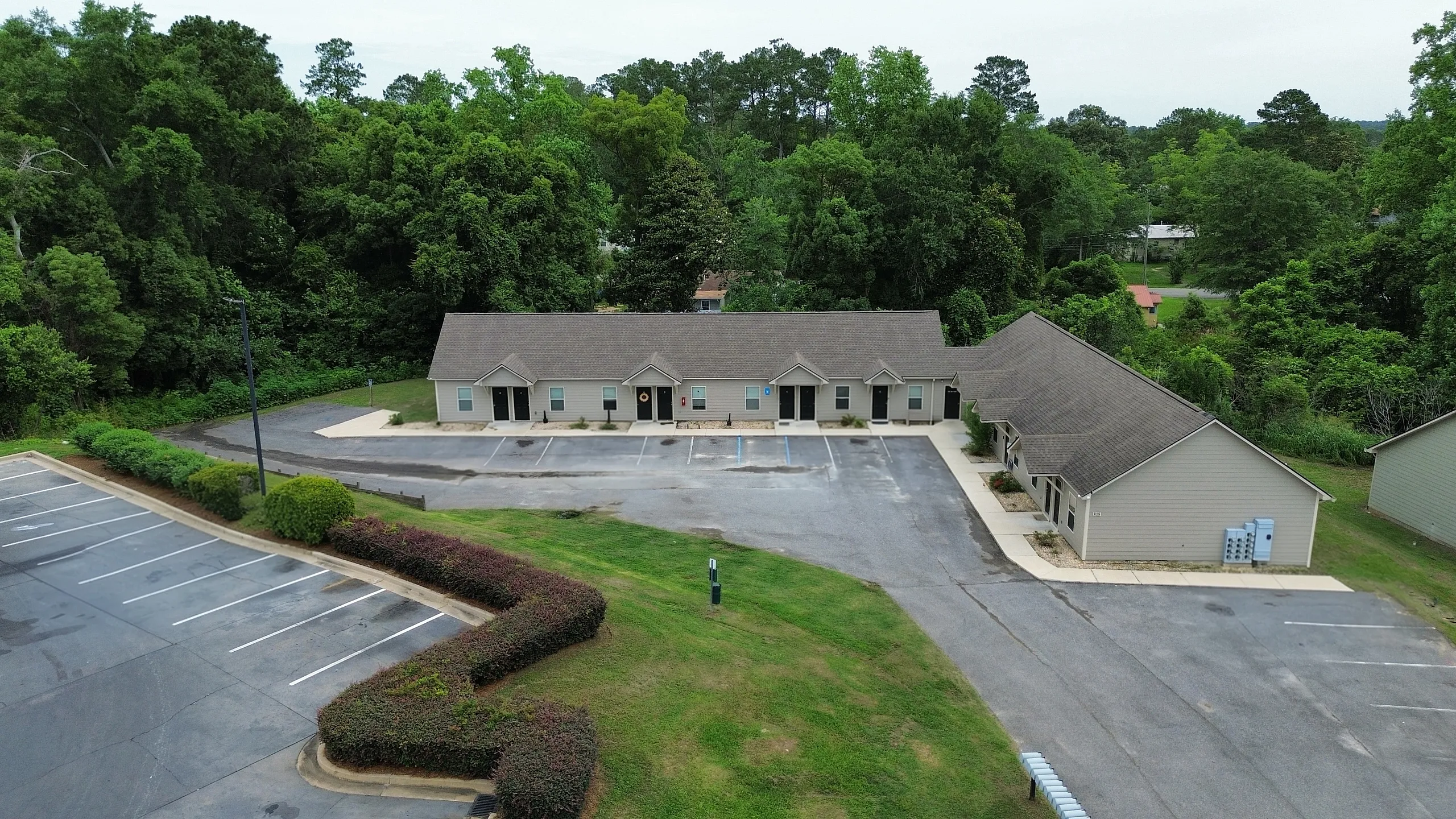 Charming apartment complex surrounded by lush greenery, featuring convenient parking and welcoming entrances.