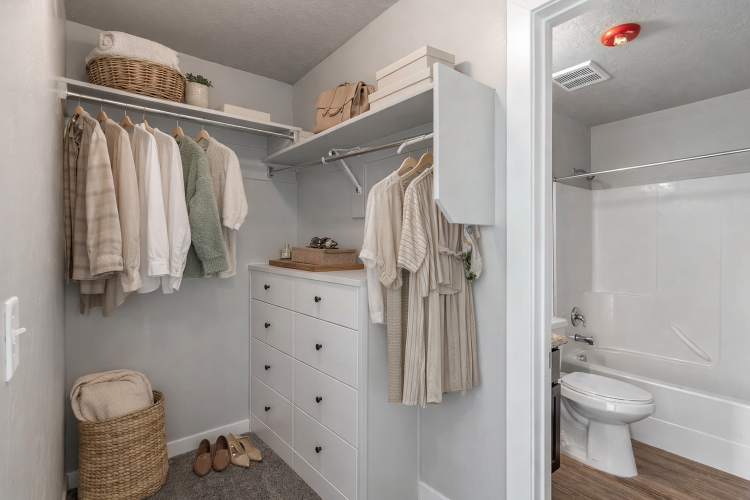 Elegant walk-in closet with ample hanging space, modern shelving, and stylish decor leading into a pristine bathroom with sleek fixtures.