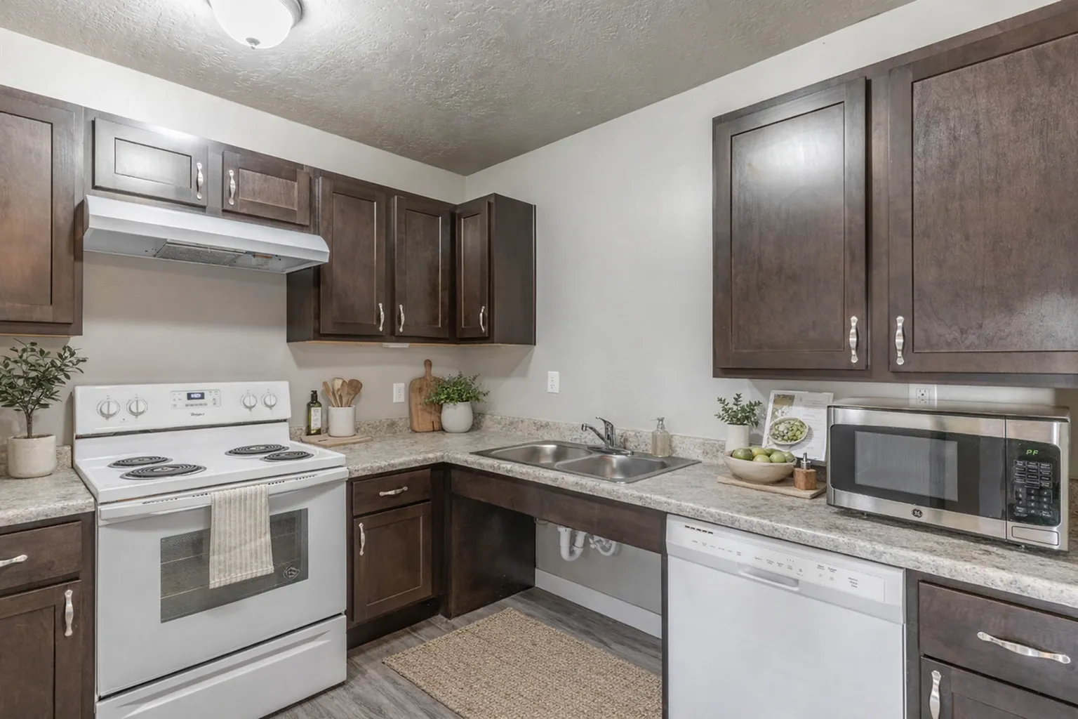 Inviting kitchen with dark wood cabinets, modern appliances, and stylish countertops showcasing a warm and functional cooking space.
