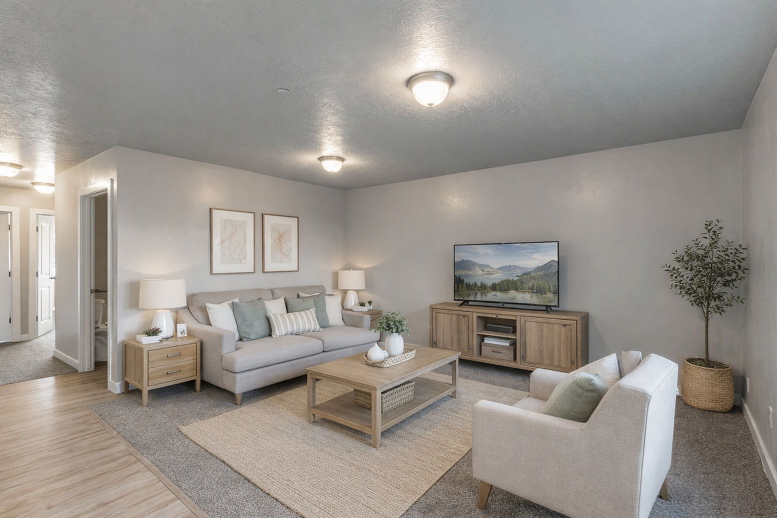 Cozy and elegant living room with modern decor, featuring a comfortable grey sofa, light wood furniture, and a flatscreen TV.