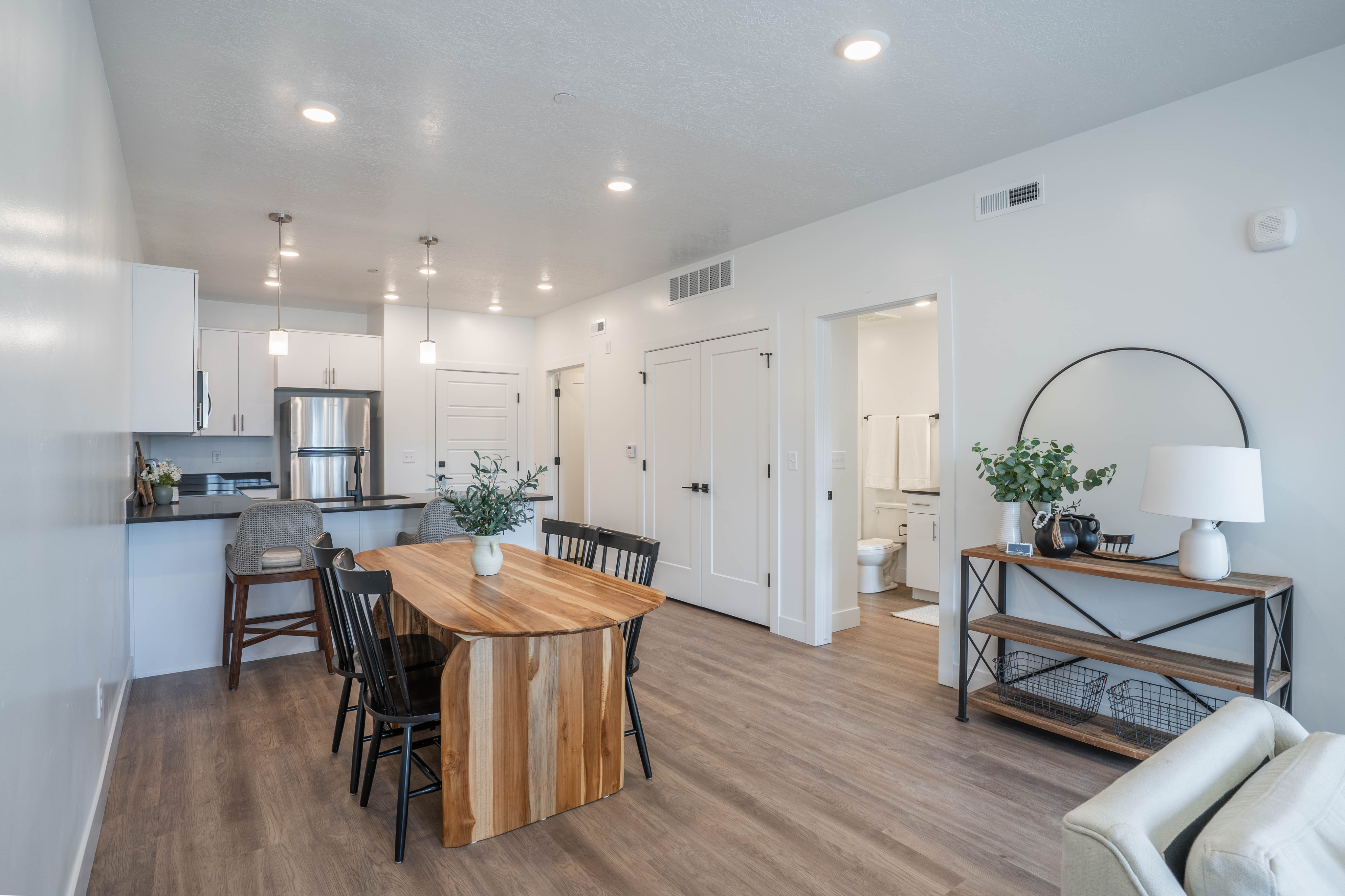 Modern open-concept dining and kitchen area featuring sleek lighting and a warm wooden table, perfect for gatherings.