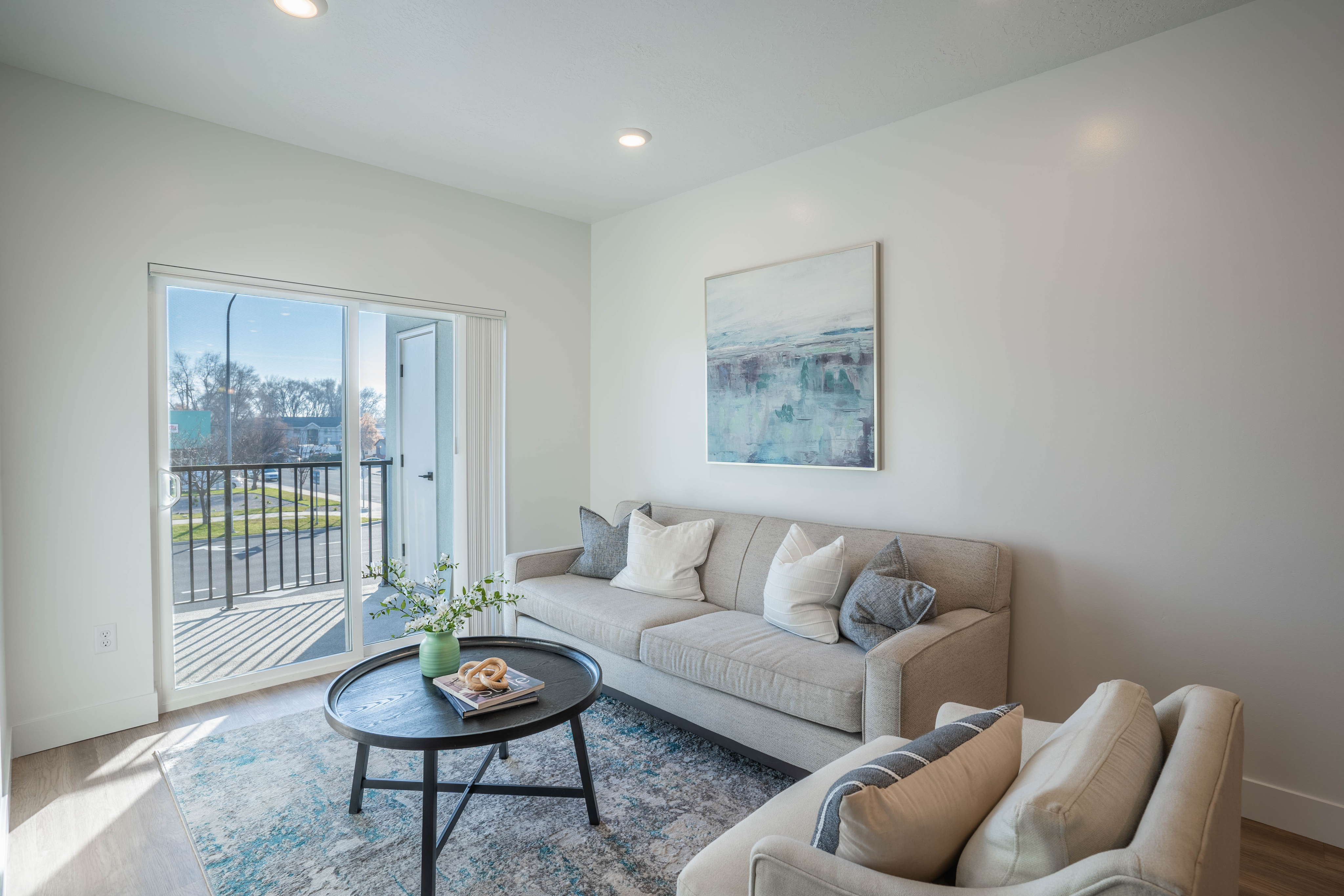 Bright and welcoming living room featuring modern decor, comfortable seating, and a view of the outdoor balcony.