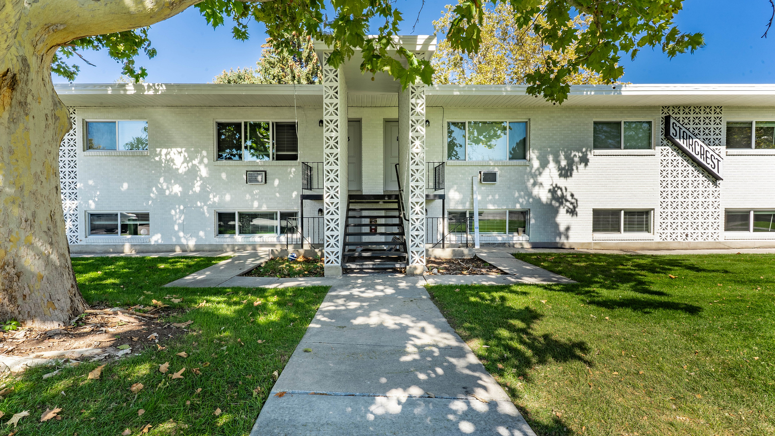 Charming mid-century modern apartment building with stylish geometric facade and lush green surroundings, perfect for serene living.