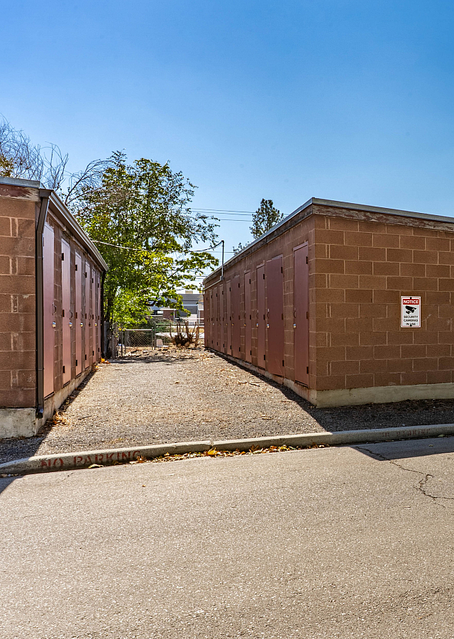 Charming exterior shot of brick storage units with secure doors and a serene outdoor setting.