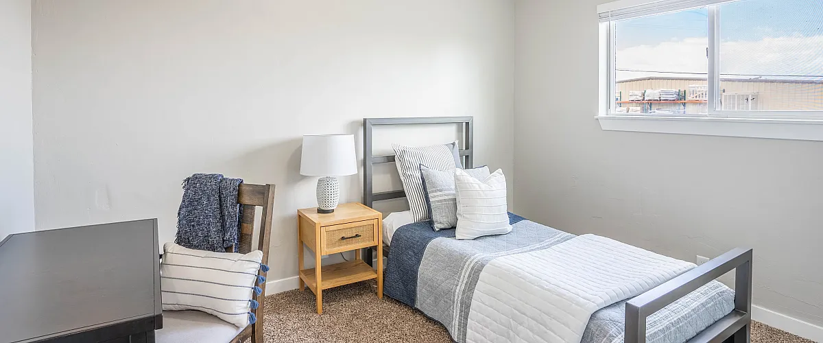 Bright and cozy bedroom with a modern single bed, elegant nightstand, and inviting natural light through the window.