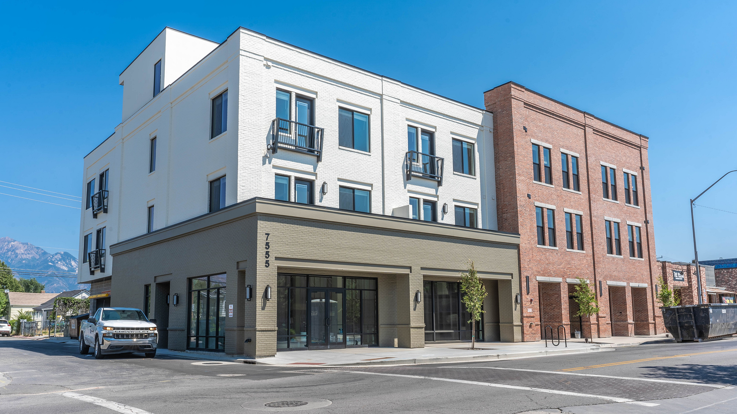 Charming urban apartment building with modern architecture, featuring clean lines and inviting balconies against a clear blue sky backdrop.