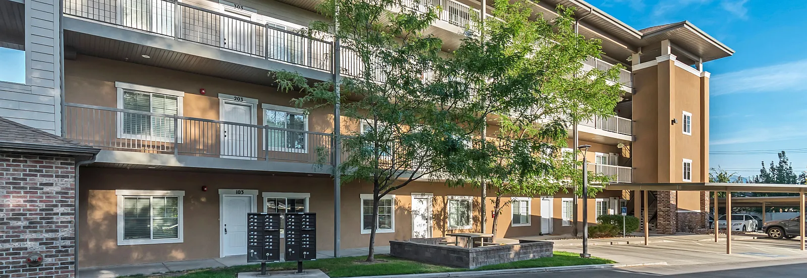 Inviting apartment complex with modern balconies, lush greenery, and convenient parking in a tranquil setting.