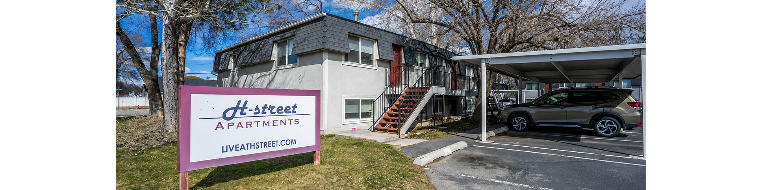 Charming exterior view of H-Street Apartments with a spacious parking area and inviting surroundings.