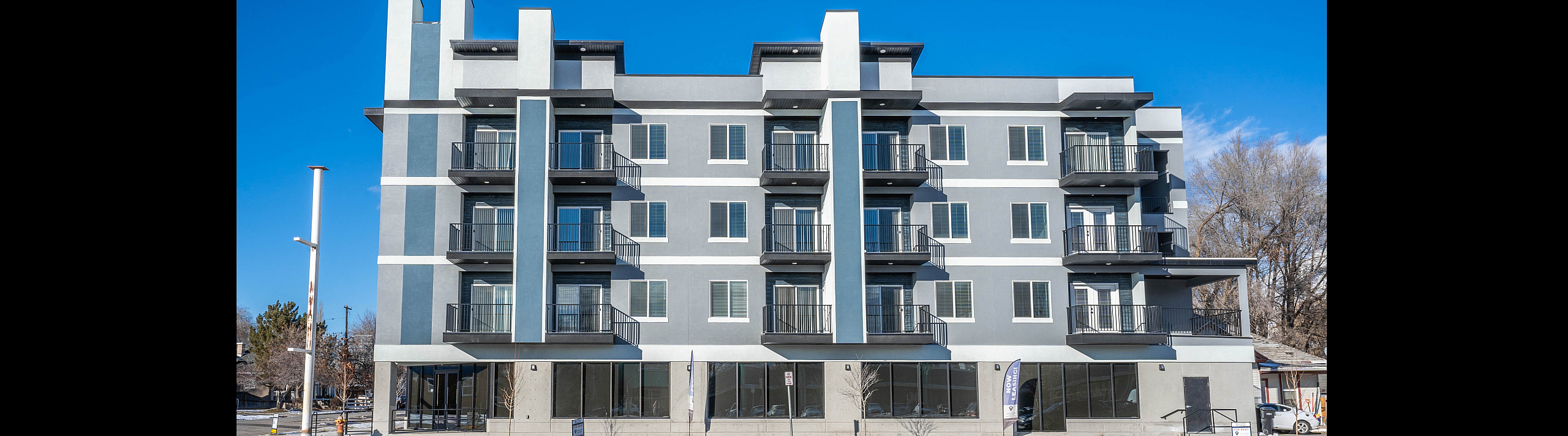Contemporary multi-story apartment building with private balconies and large windows under a clear blue sky, perfect for modern urban living.