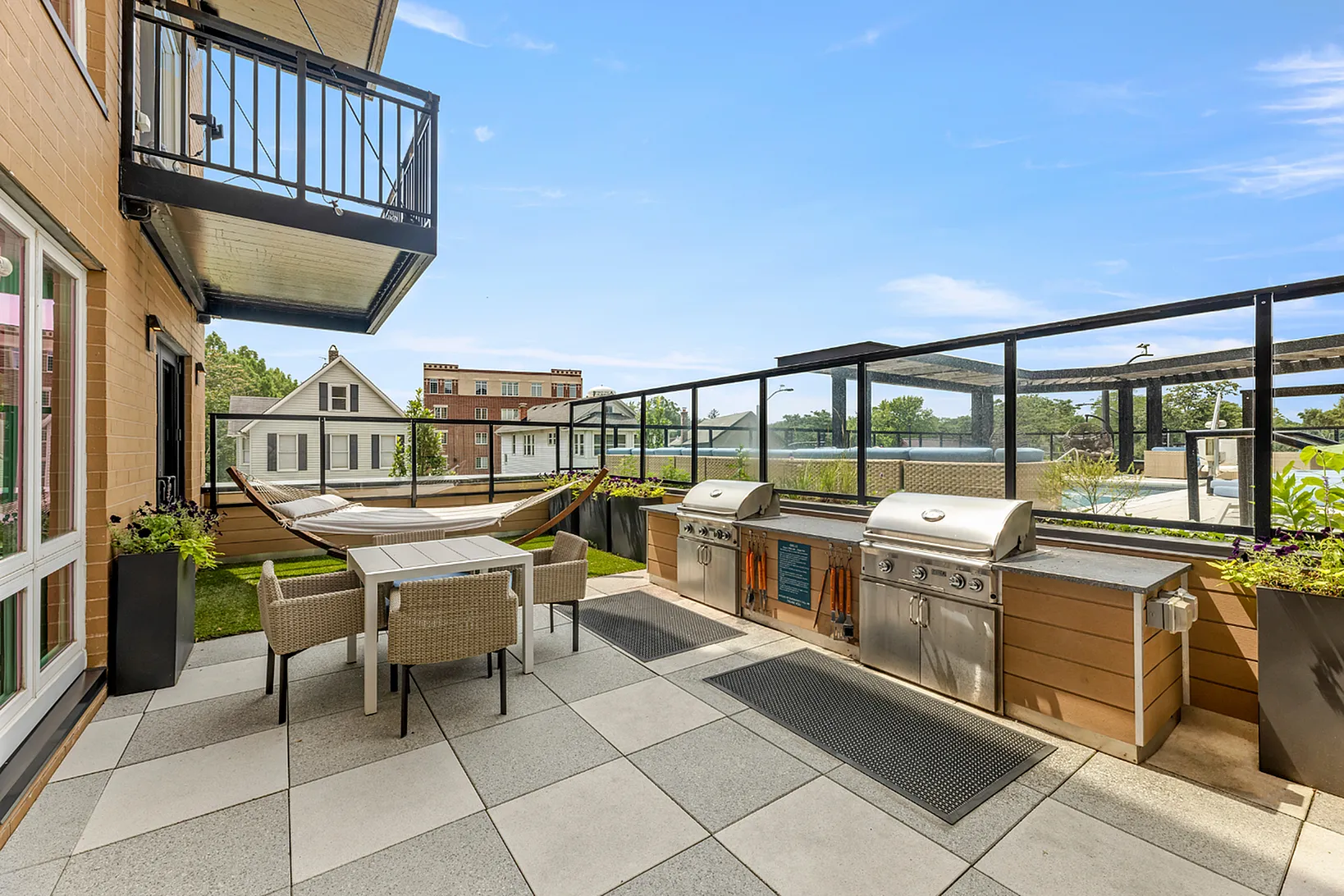 Chic outdoor patio featuring modern grills, elegant dining area, and a relaxing hammock, ideal for entertaining.