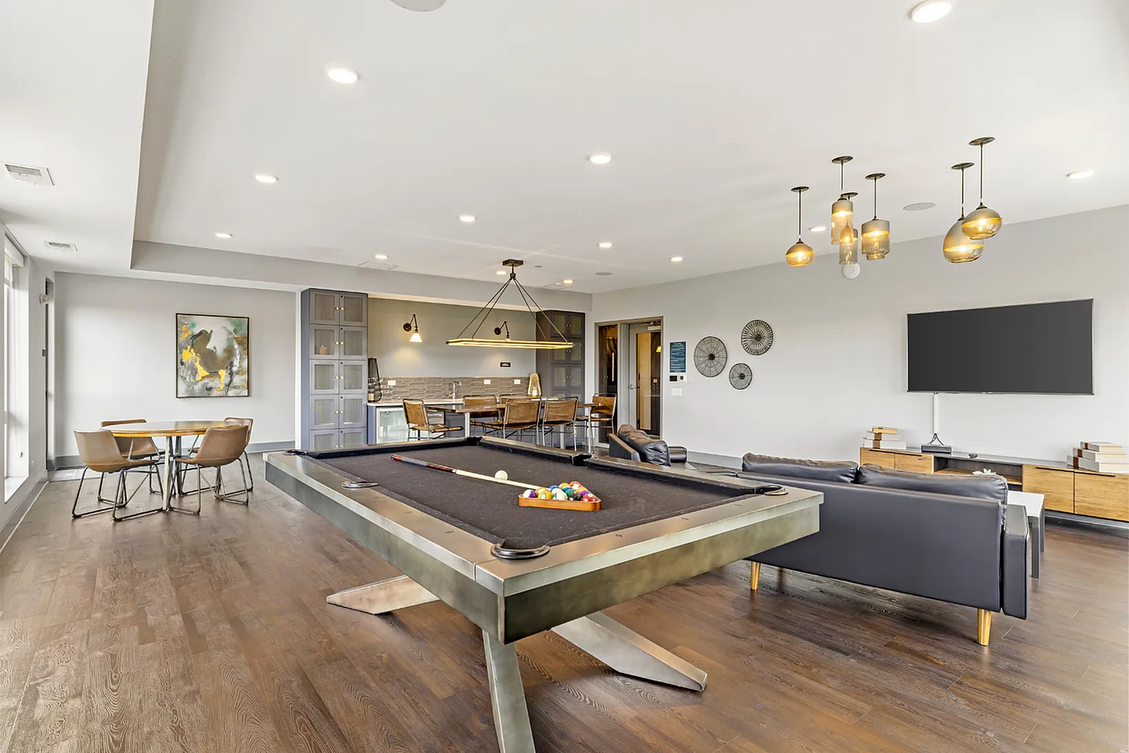Elegant entertainment room with a modern pool table, stylish seating, and chic lighting fixtures, perfect for social gatherings.