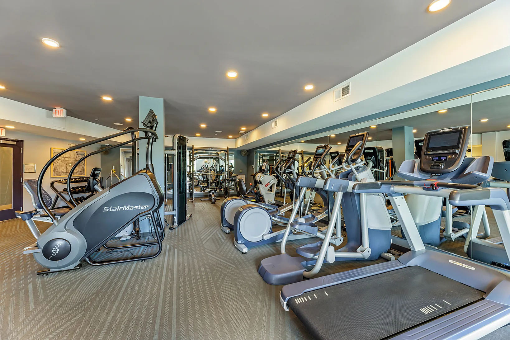 Modern fitness center featuring state-of-the-art exercise equipment, including treadmills and StairMasters, under bright overhead lighting.