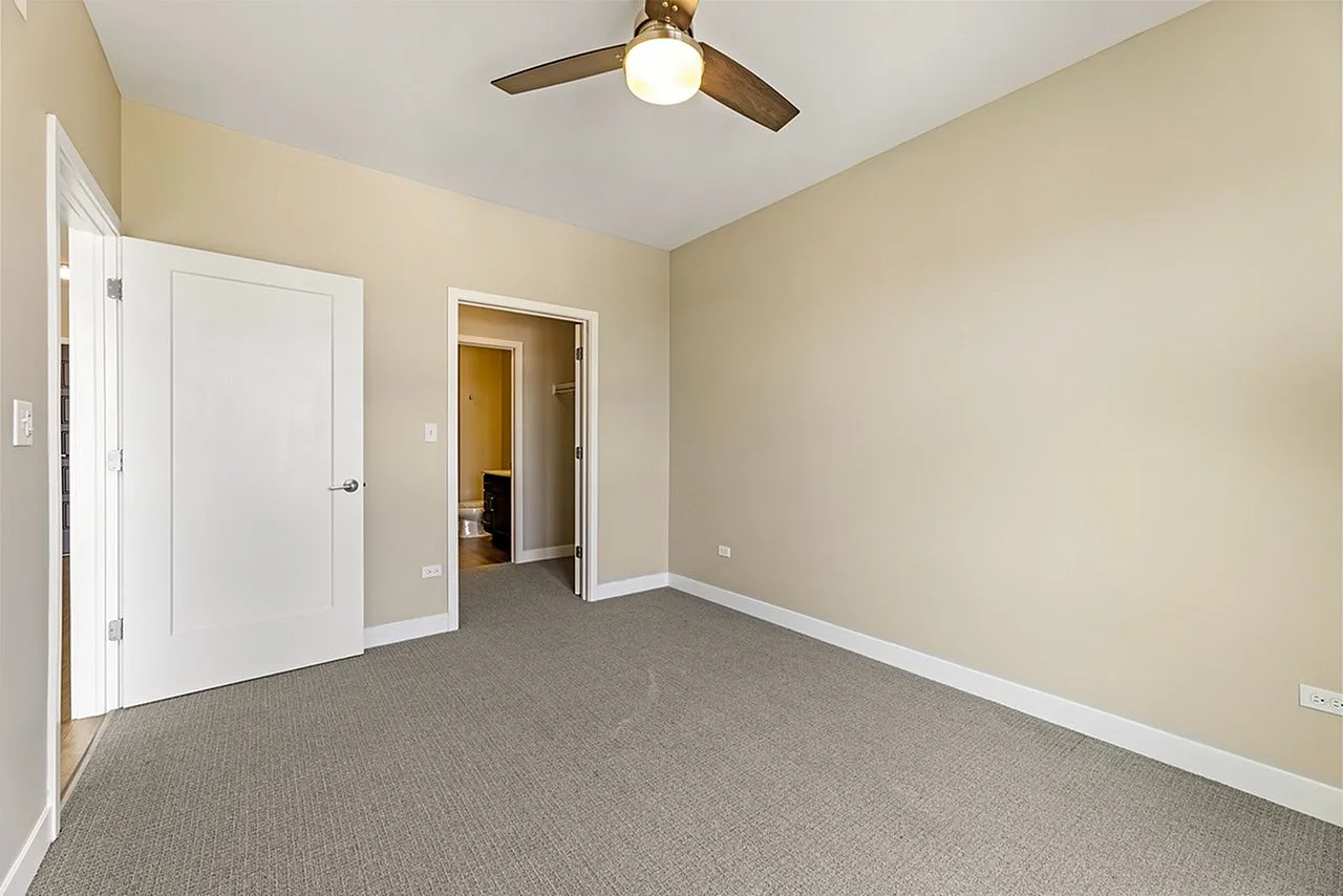 Bright and inviting bedroom with soft carpet, modern ceiling fan, and ample closet space, perfect for relaxation.