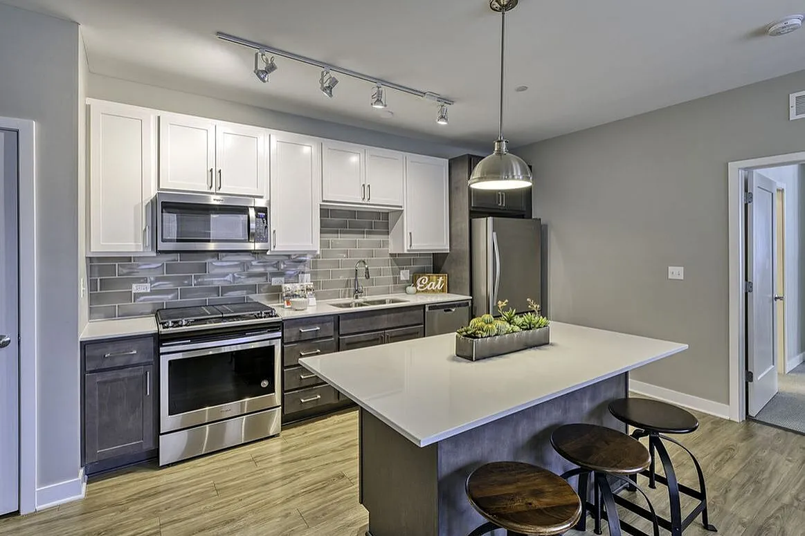 Modern kitchen with sleek cabinetry, stainless steel appliances, a stylish backsplash, and a chic breakfast bar with pendant lighting.
