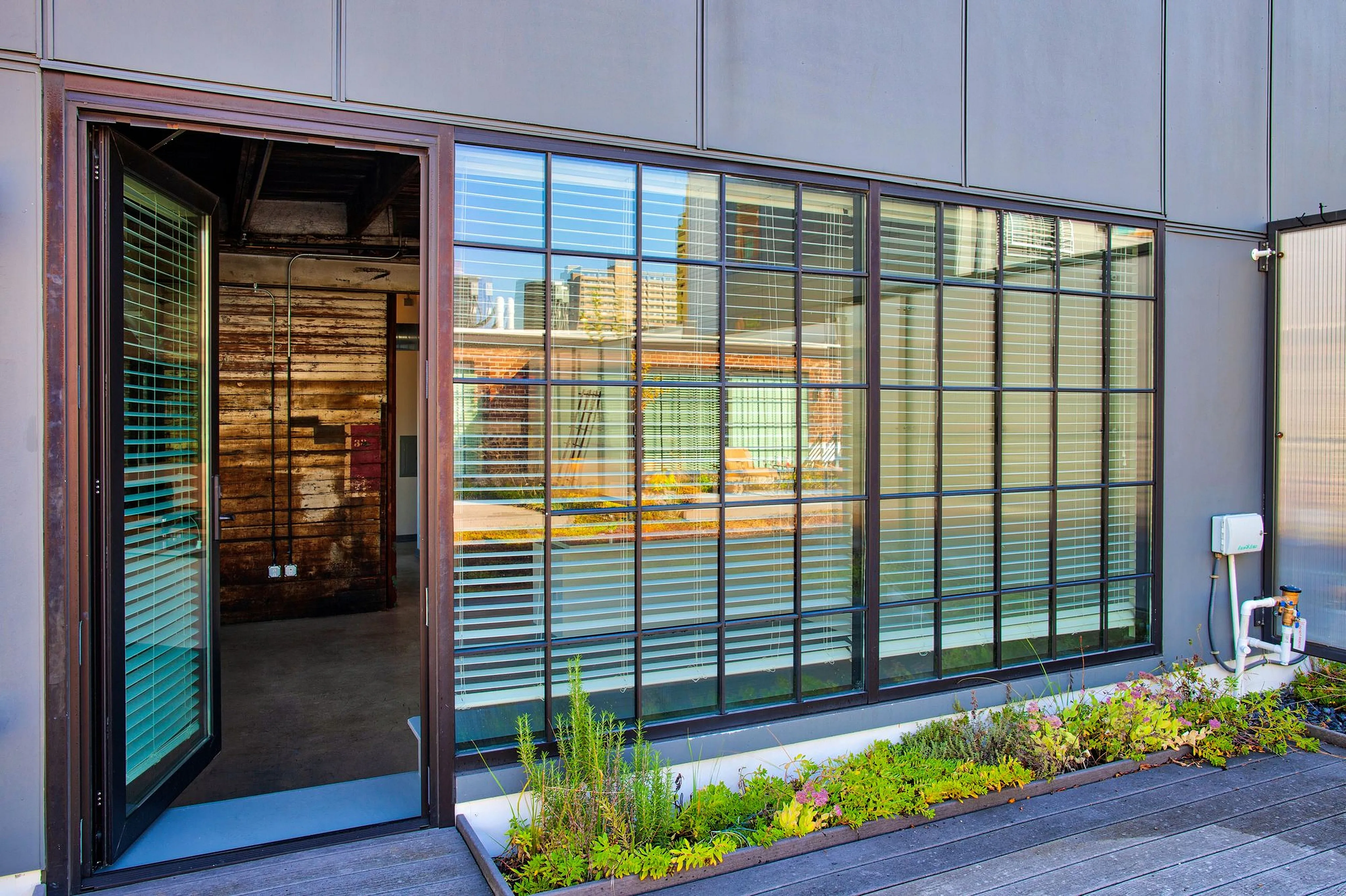Contemporary apartment exterior with large windows and lush planter box, showcasing urban design and outdoor charm.