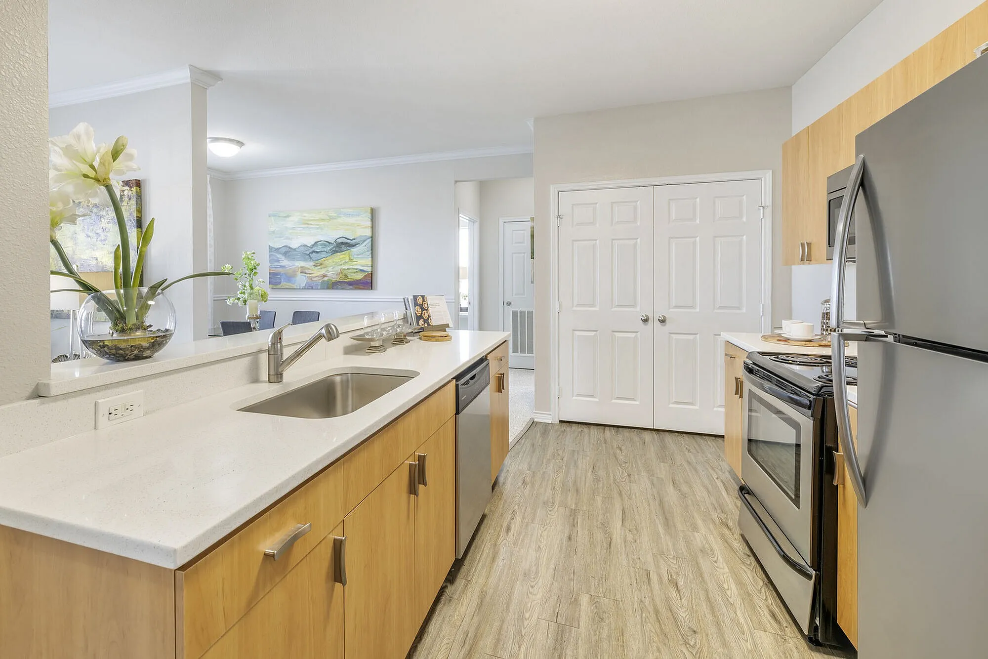 Modern kitchen with sleek stainless steel appliances, elegant light wood cabinets, and a spacious island overlooking a cozy dining area.
