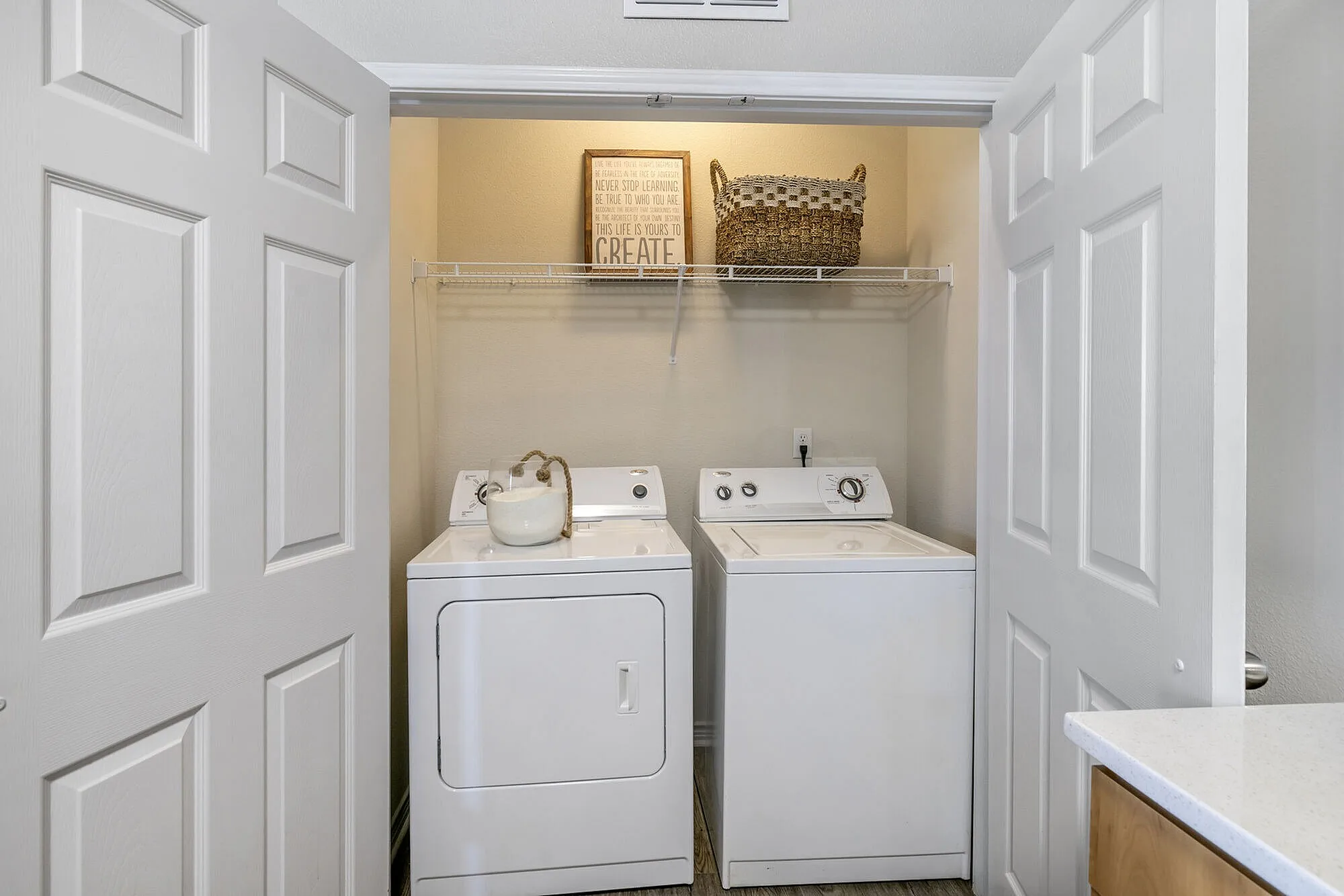 Charming laundry nook with modern washer and dryer, accented by a decorative basket and inspirational wall art.