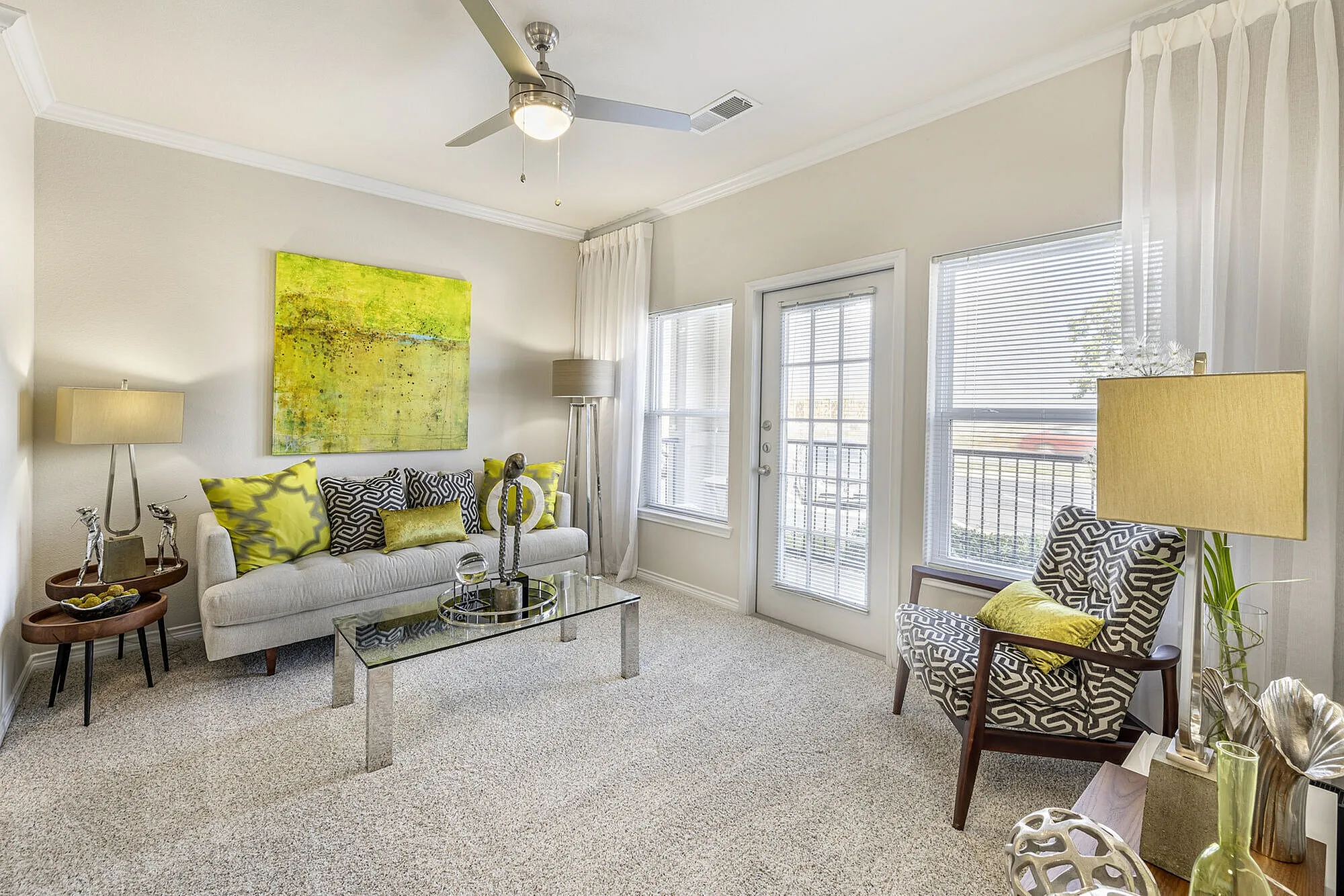 Bright and modern living room with elegant decor, featuring a cozy sofa, chic armchair, and vibrant artwork, complemented by large windows and natural light.