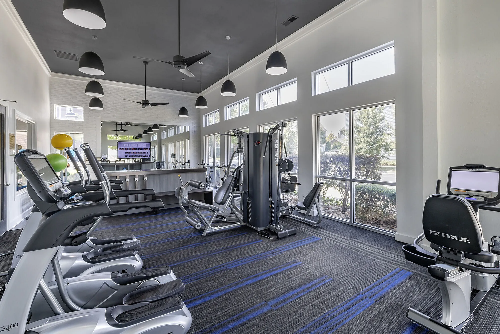 Modern fitness center featuring state-of-the-art cardio and strength training equipment, abundant natural light, and stylish design.