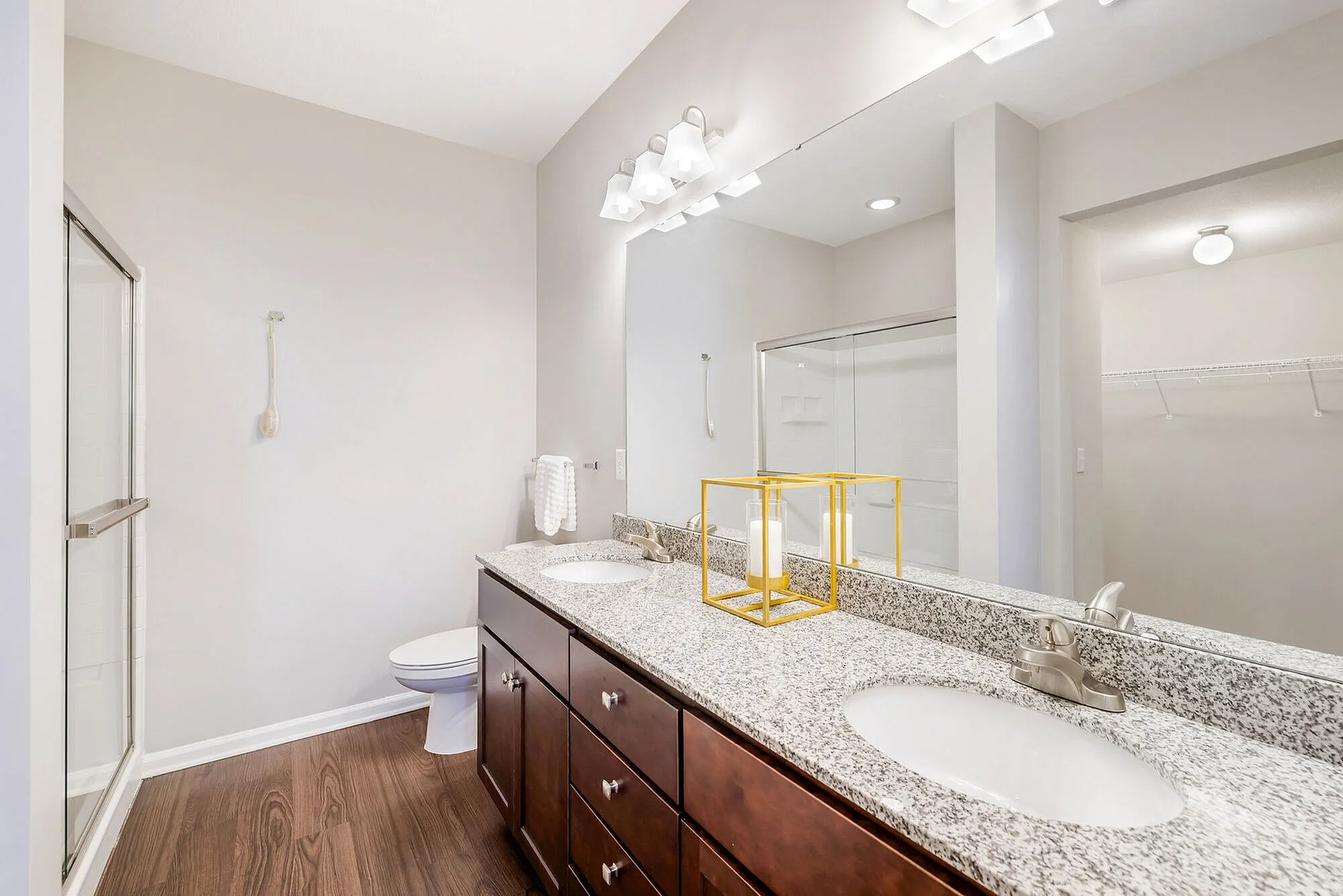 Elegant bathroom featuring a double granite vanity, modern lighting, and a spacious glass-enclosed shower.