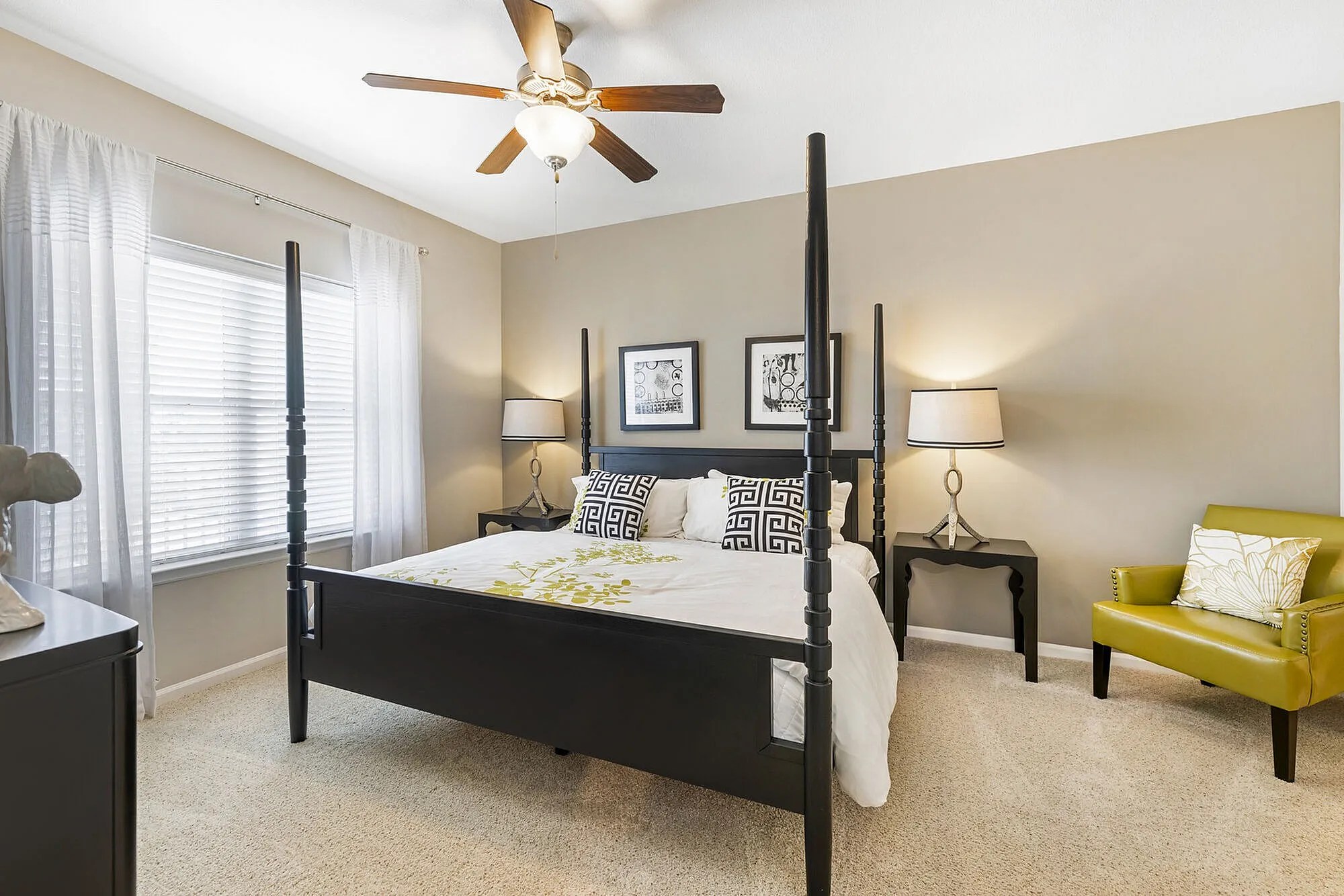 Elegant bedroom with a stylish four-poster bed, warm lighting from sleek table lamps, and a cozy green accent chair, creating a serene and inviting atmosphere.