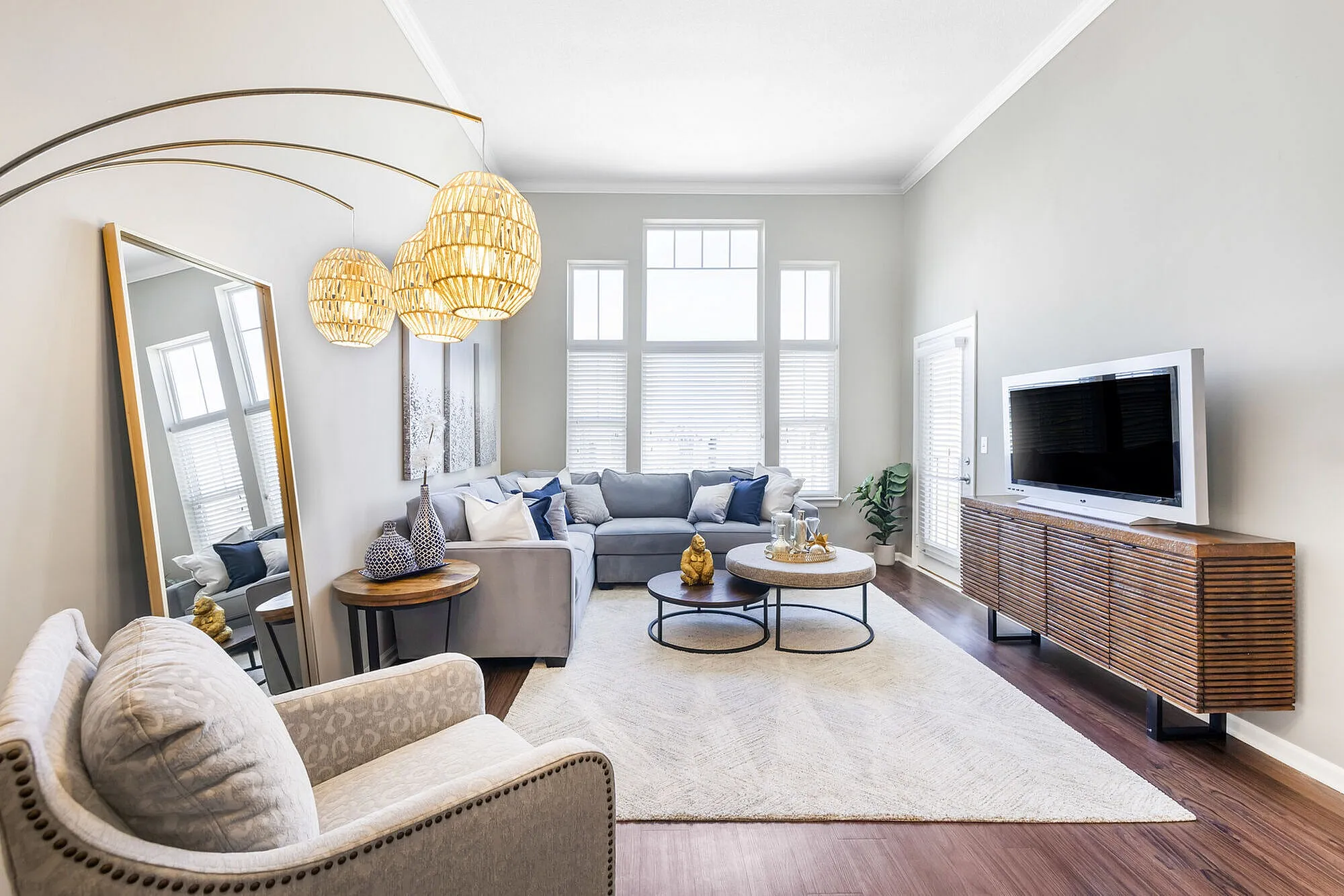 Elegant living room with modern decor, featuring a cozy sectional sofa, stylish pendant lighting, and a sleek entertainment center with a flat-screen TV.