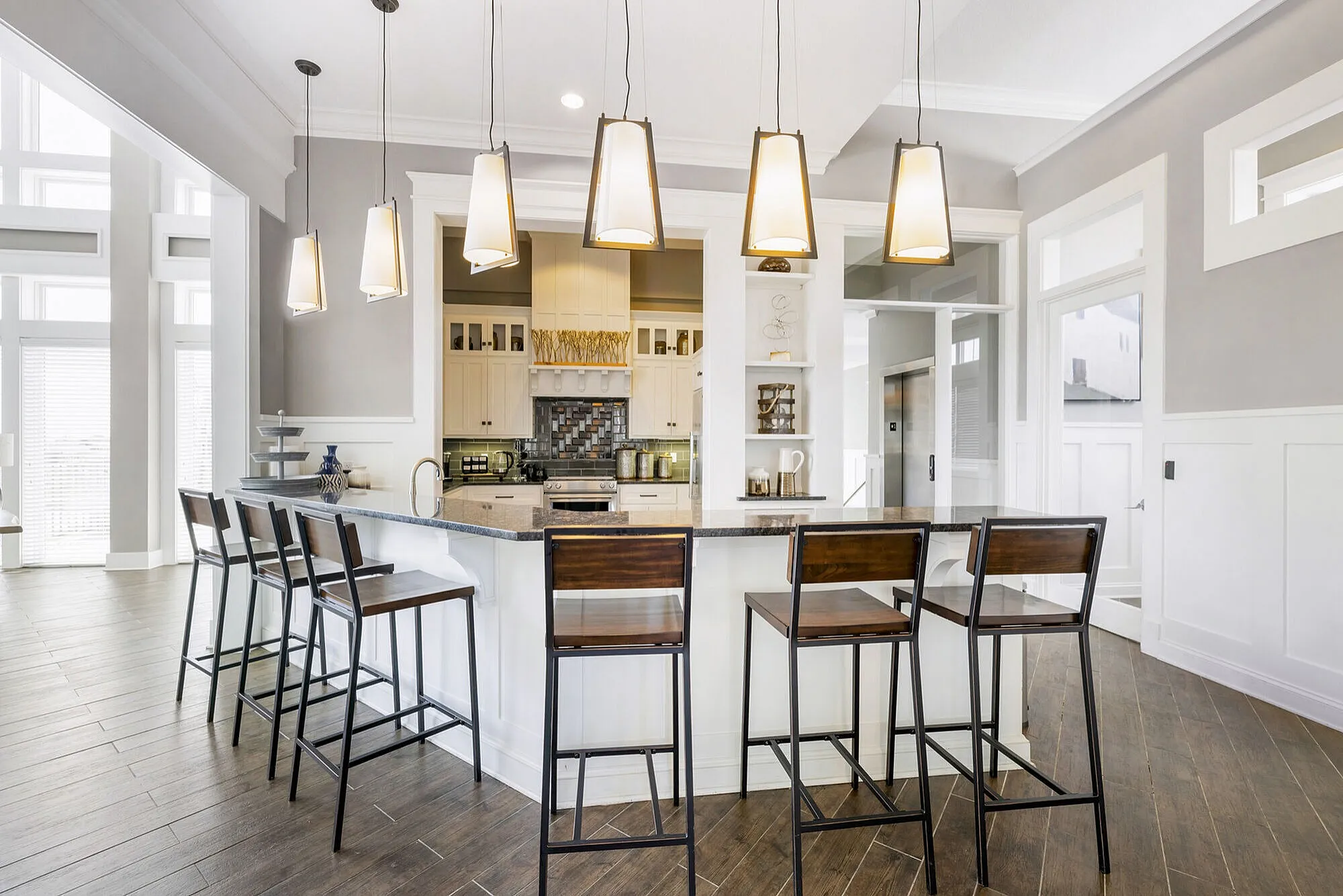 Bright and modern kitchen featuring a sleek island with seating, elegant pendant lighting, and contemporary cabinetry.