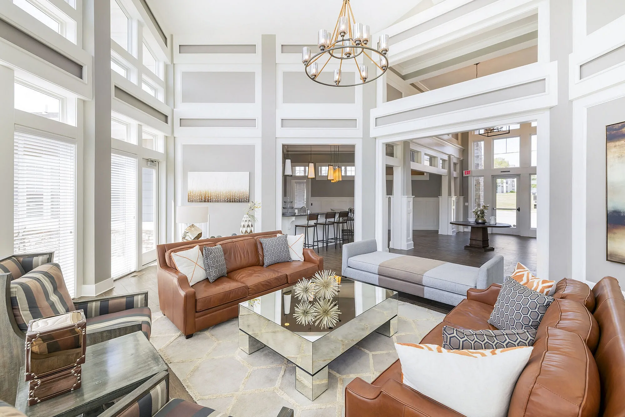 Elegant living room with high ceilings, large windows, cozy leather sofas, and a chic mirrored coffee table, perfect for entertaining.