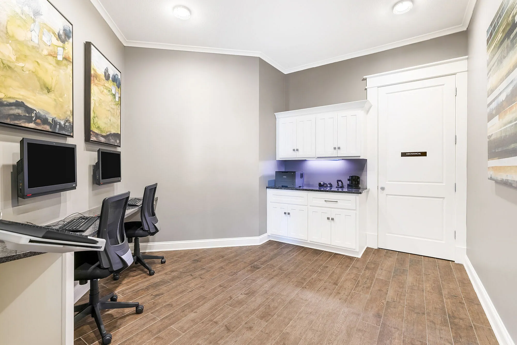 Modern apartment workspace with two computer stations, elegant wood flooring, and a sleek cabinet for storage.
