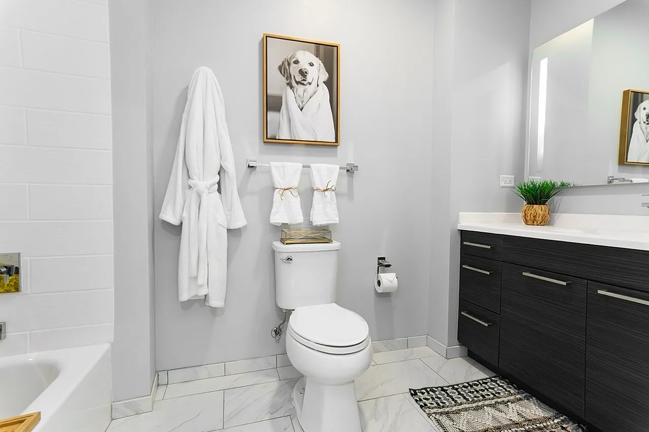 Elegant modern bathroom featuring sleek fixtures, stylish vanity, wall art, and cozy ambiance.