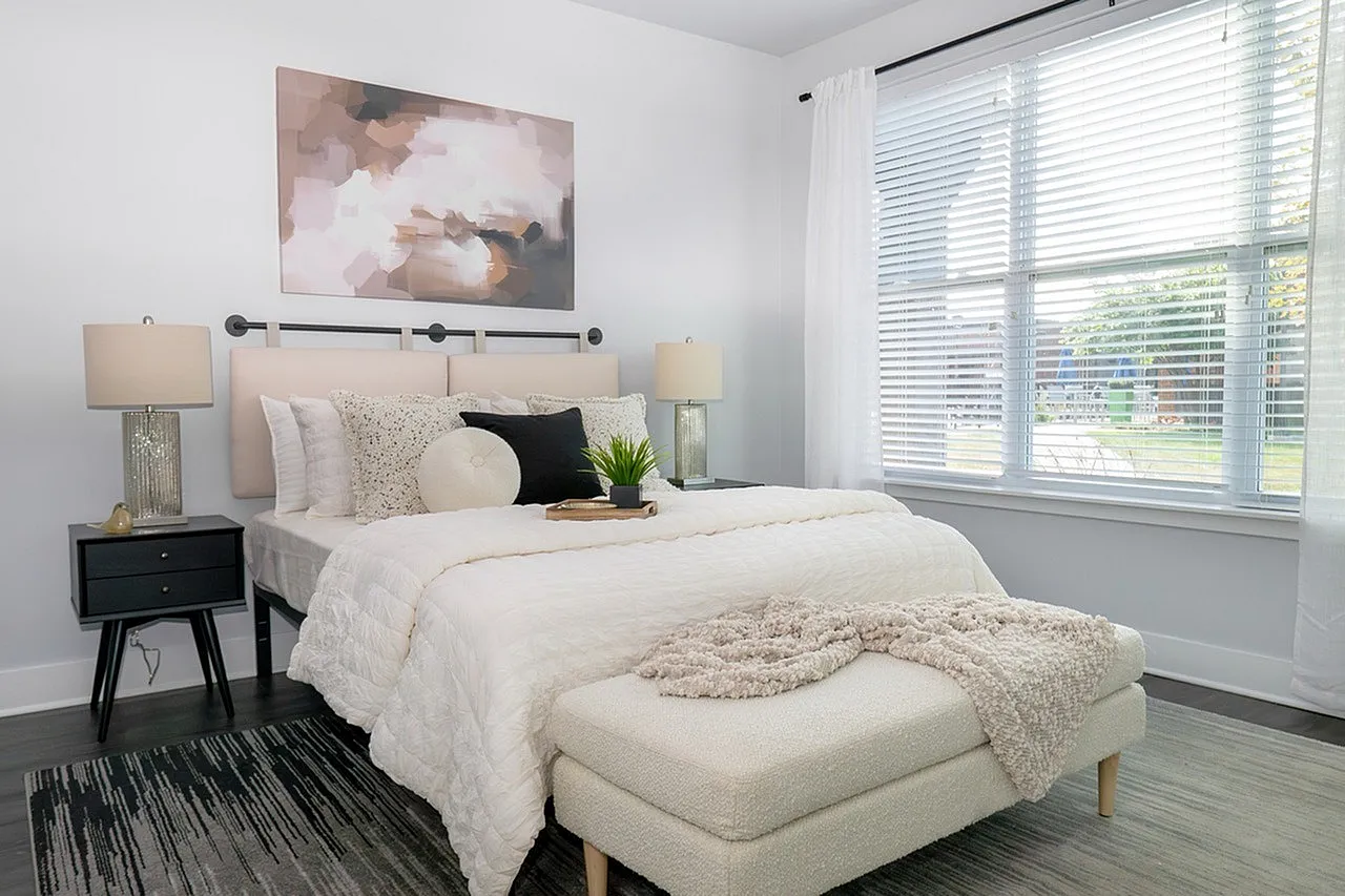 Bright and airy bedroom featuring a cozy bed, elegant decor, and expansive window with garden view.