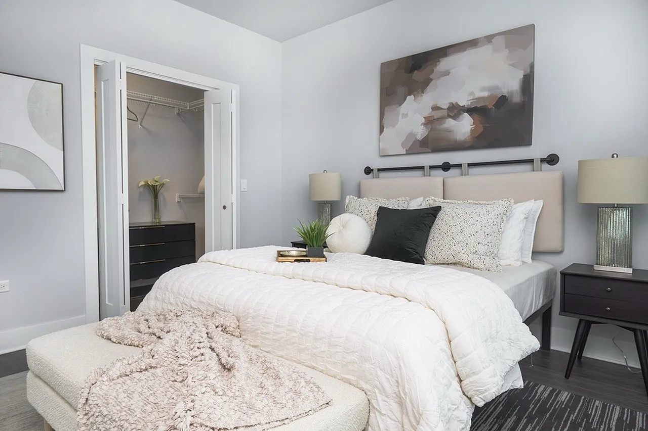 Inviting bedroom with modern decor, featuring a plush bed, stylish lamps, and a spacious walk-in closet.
