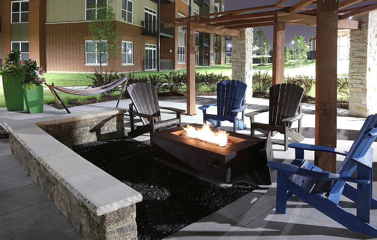 Inviting outdoor patio with cozy fire pit, Adirondack chairs, and hammock, ideal for relaxing evenings under a stylish pergola.