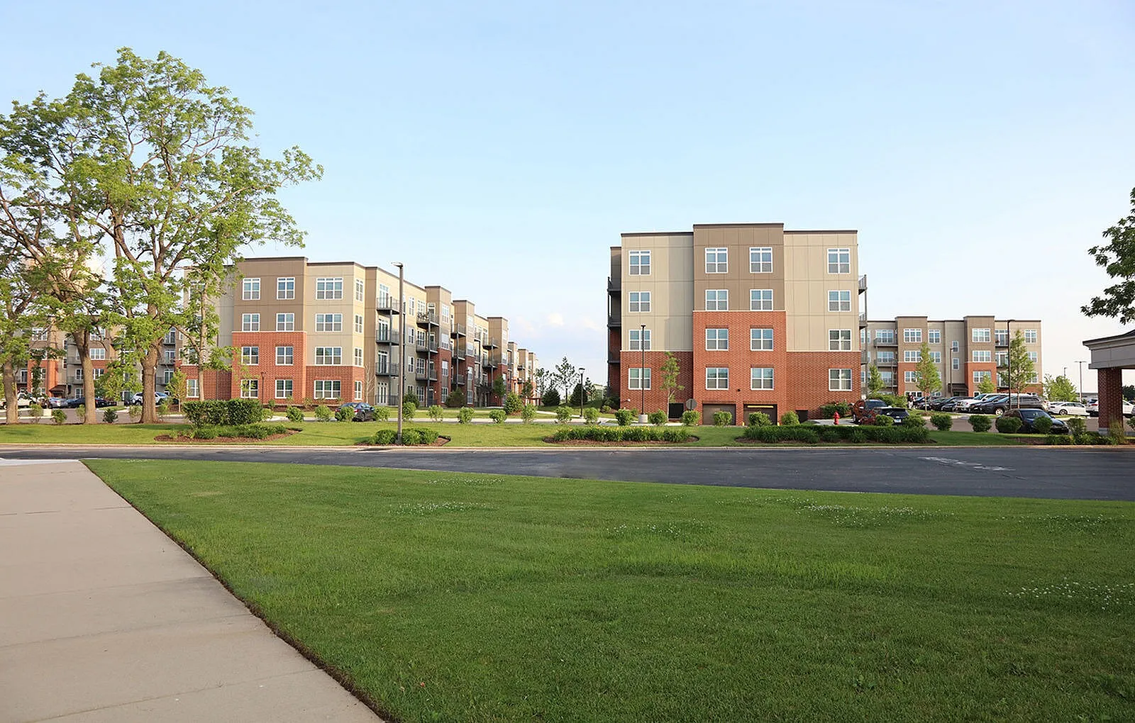 Modern apartment complex with stylish architecture, surrounded by lush greenery and well-maintained gardens, offering a serene residential experience.