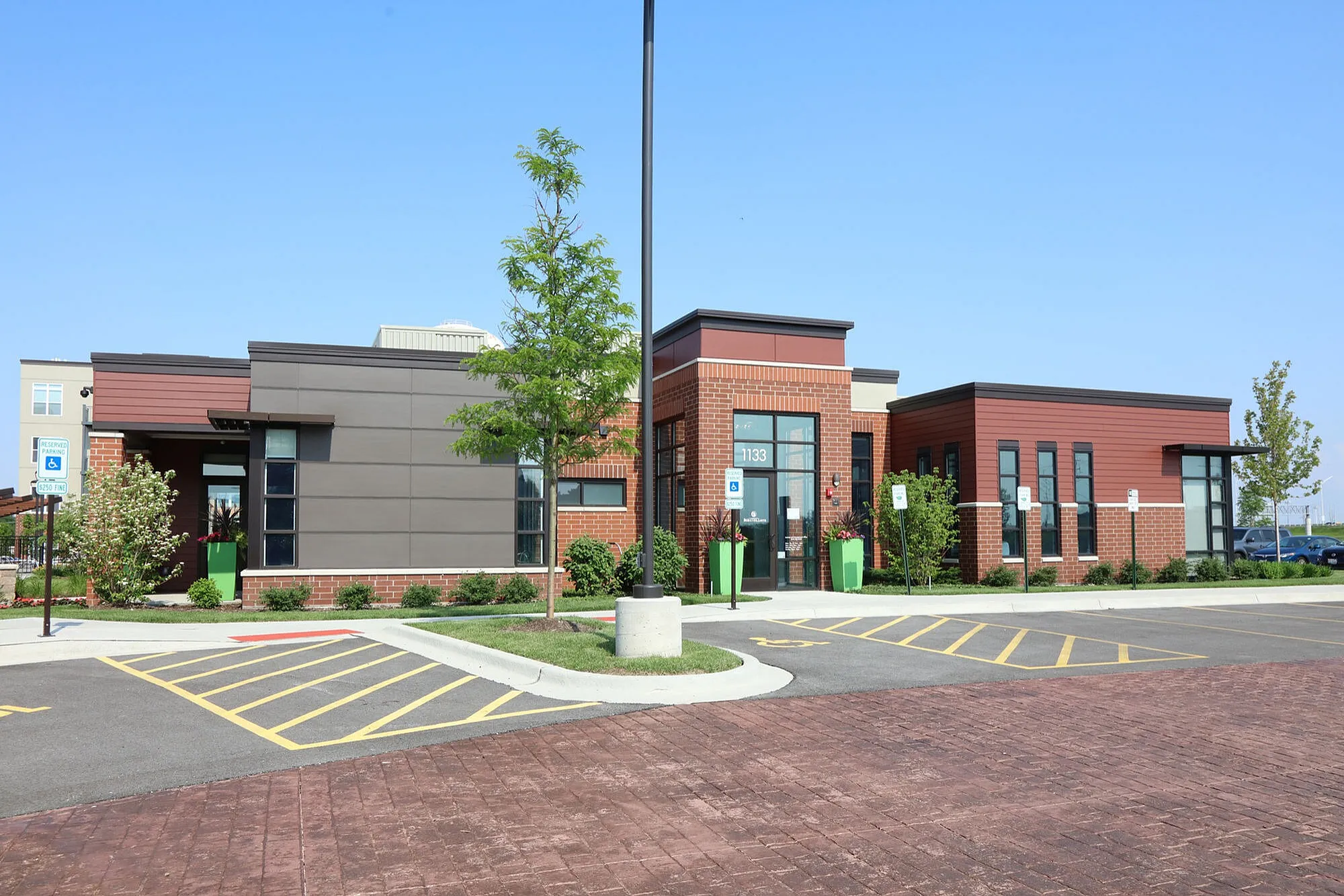 Modern apartment complex featuring elegant brick and panel exterior with lush landscaping and accessible parking.