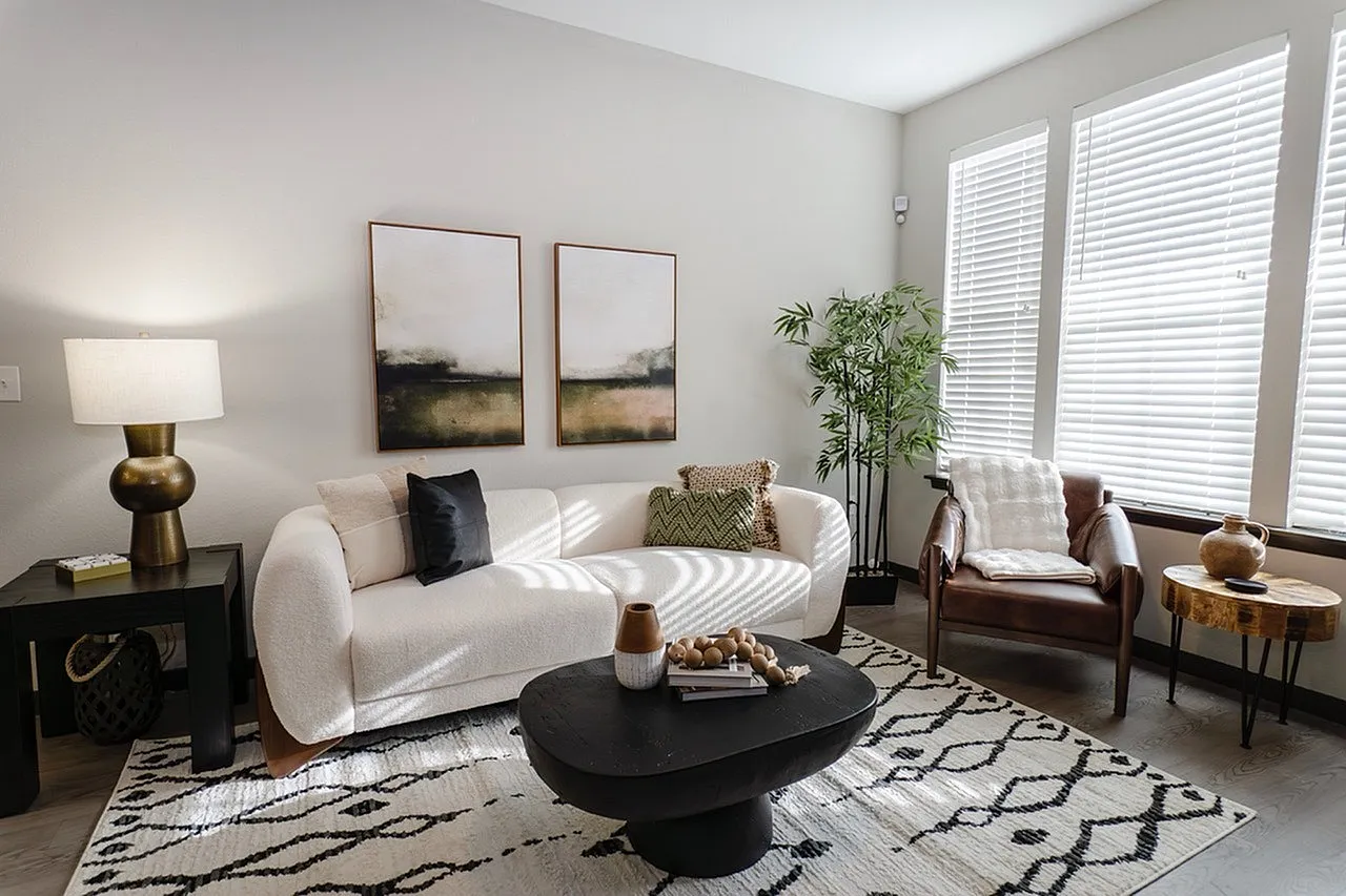 Chic living room with a modern white sofa, stylish black coffee table, and abstract art, bathed in natural light.