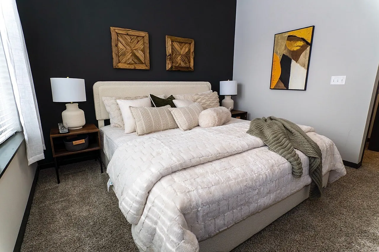 Cozy and elegant bedroom with plush bedding, stylish lamps, and modern artwork, offering a serene retreat.