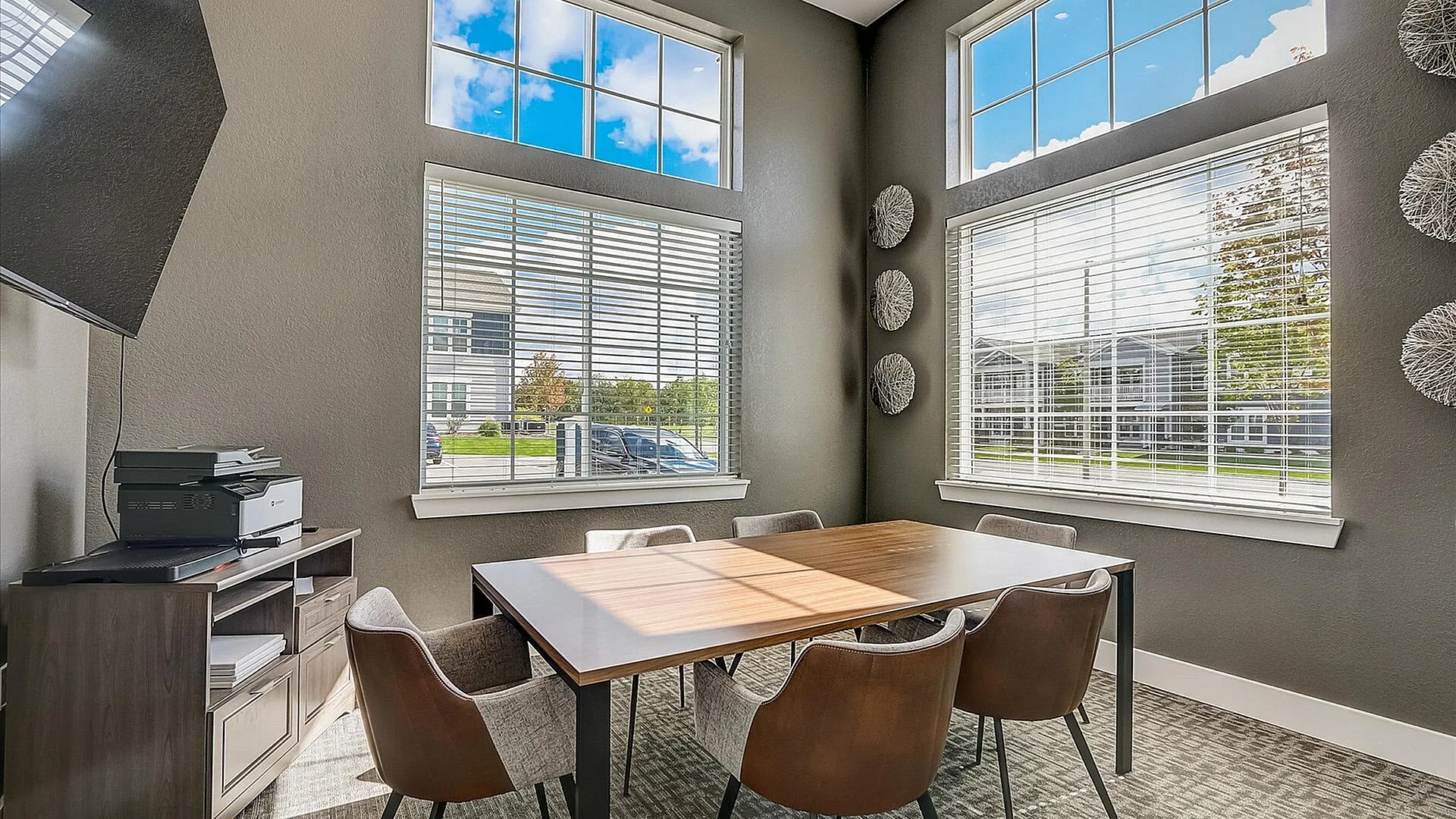 Bright, modern office space with large windows, elegant wooden table, and comfortable chairs, offering a perfect setting for productivity and creativity.