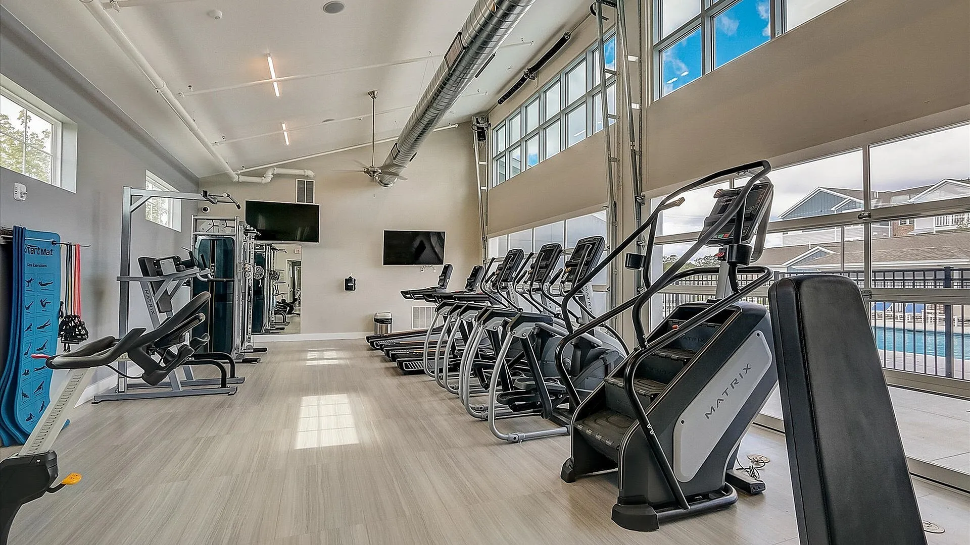 Bright and modern fitness center with top-of-the-line exercise equipment, large windows, and sleek flooring, offering an invigorating workout experience.