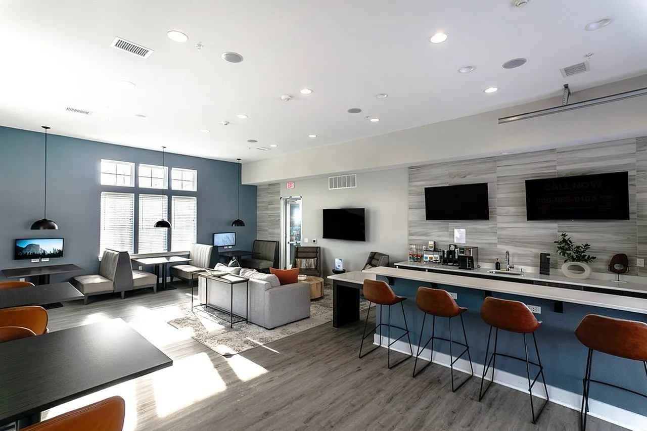 Modern community lounge with a bright, spacious interior, featuring sleek seating, ample natural light, and a stylish bar area with high stools.