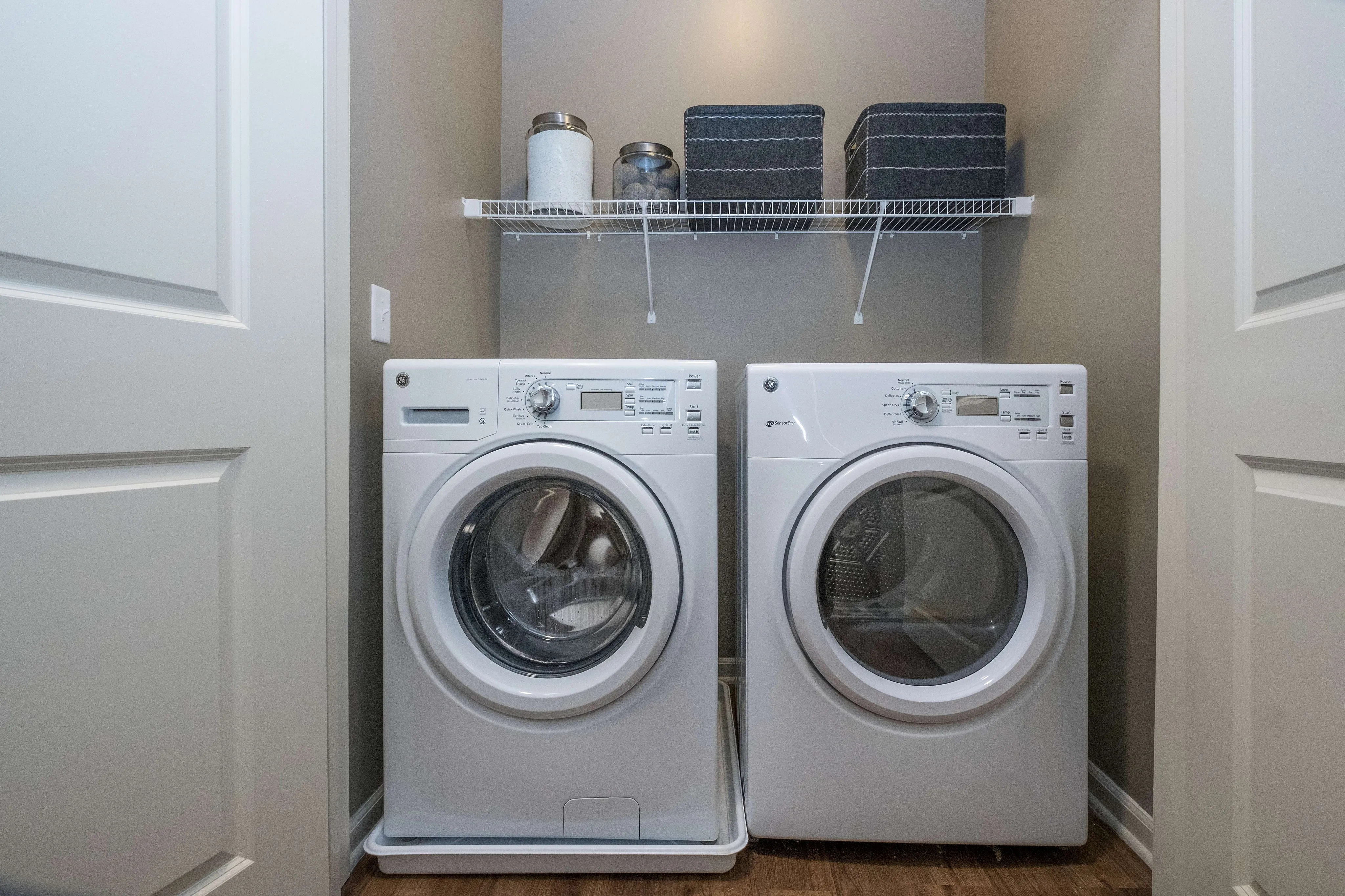 Modern laundry room with sleek washer and dryer set, featuring stylish shelving for organized storage.