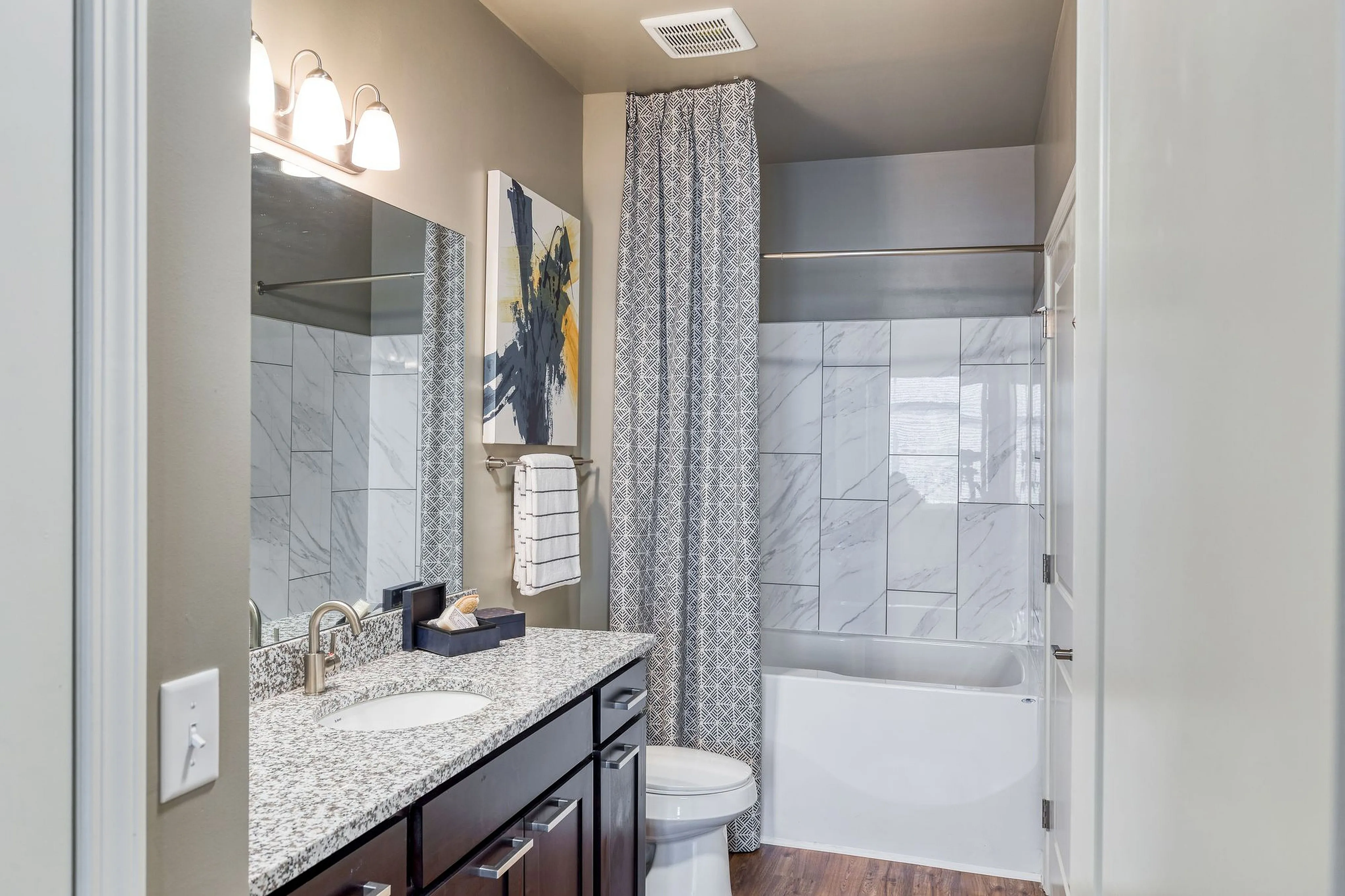 Chic bathroom design featuring a granite countertop, modern fixtures, and elegant marble tile accents with a stylish shower curtain.