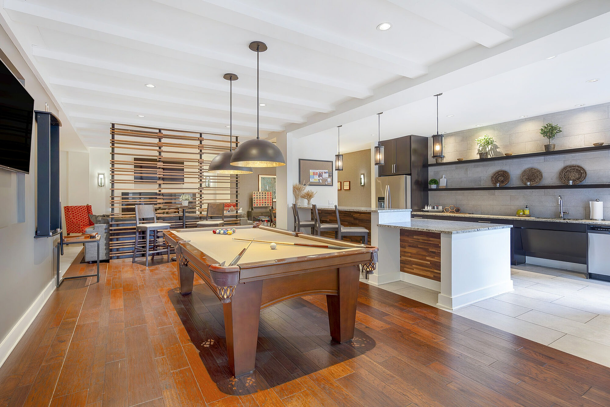 Modern entertainment space with a stylish billiards table, elegant lighting, and a sleek kitchen with contemporary finishes.