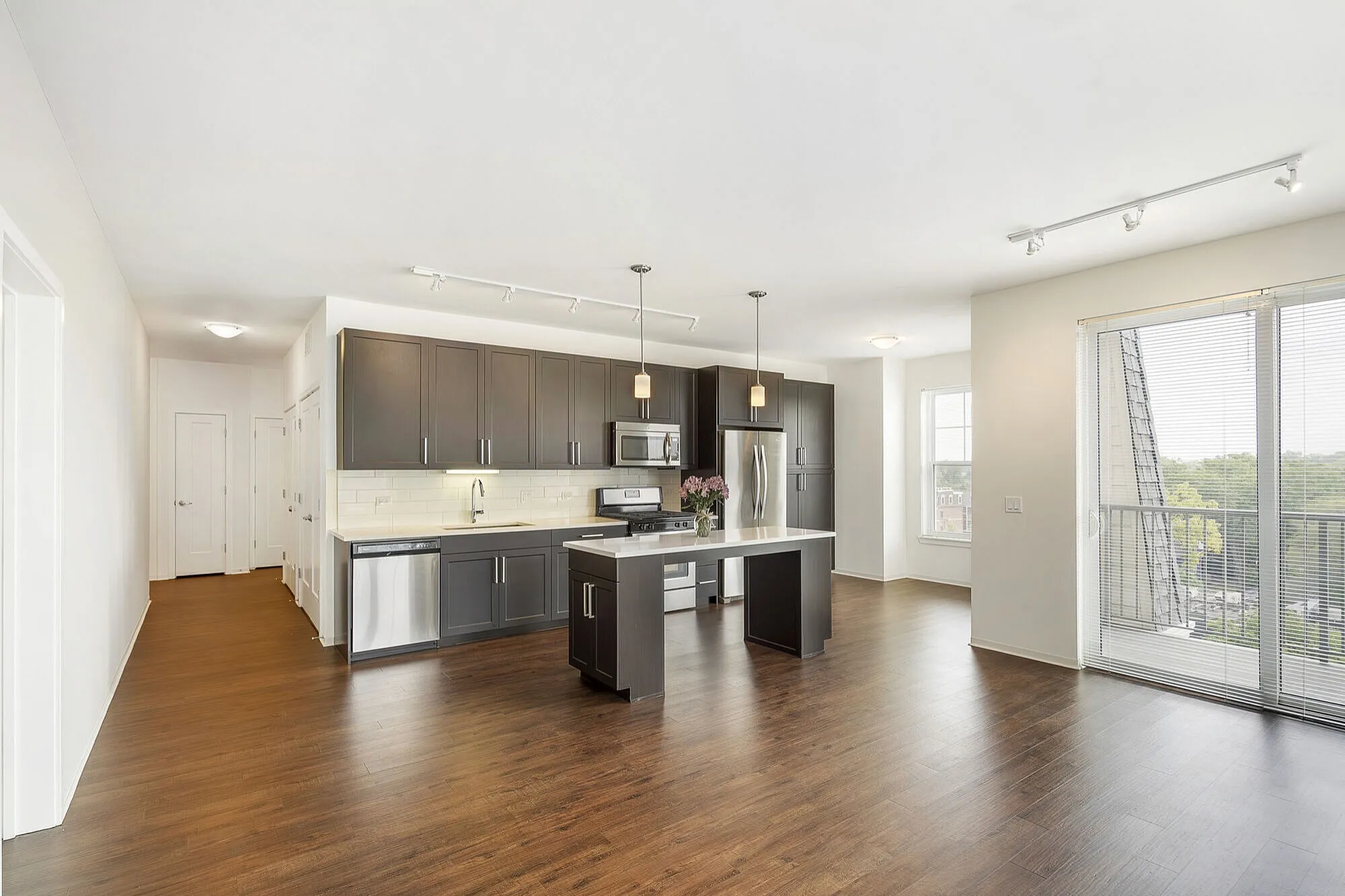 Bright modern kitchen with dark cabinets, stainless steel appliances, and an elegant island, overlooking a large window with scenic views.
