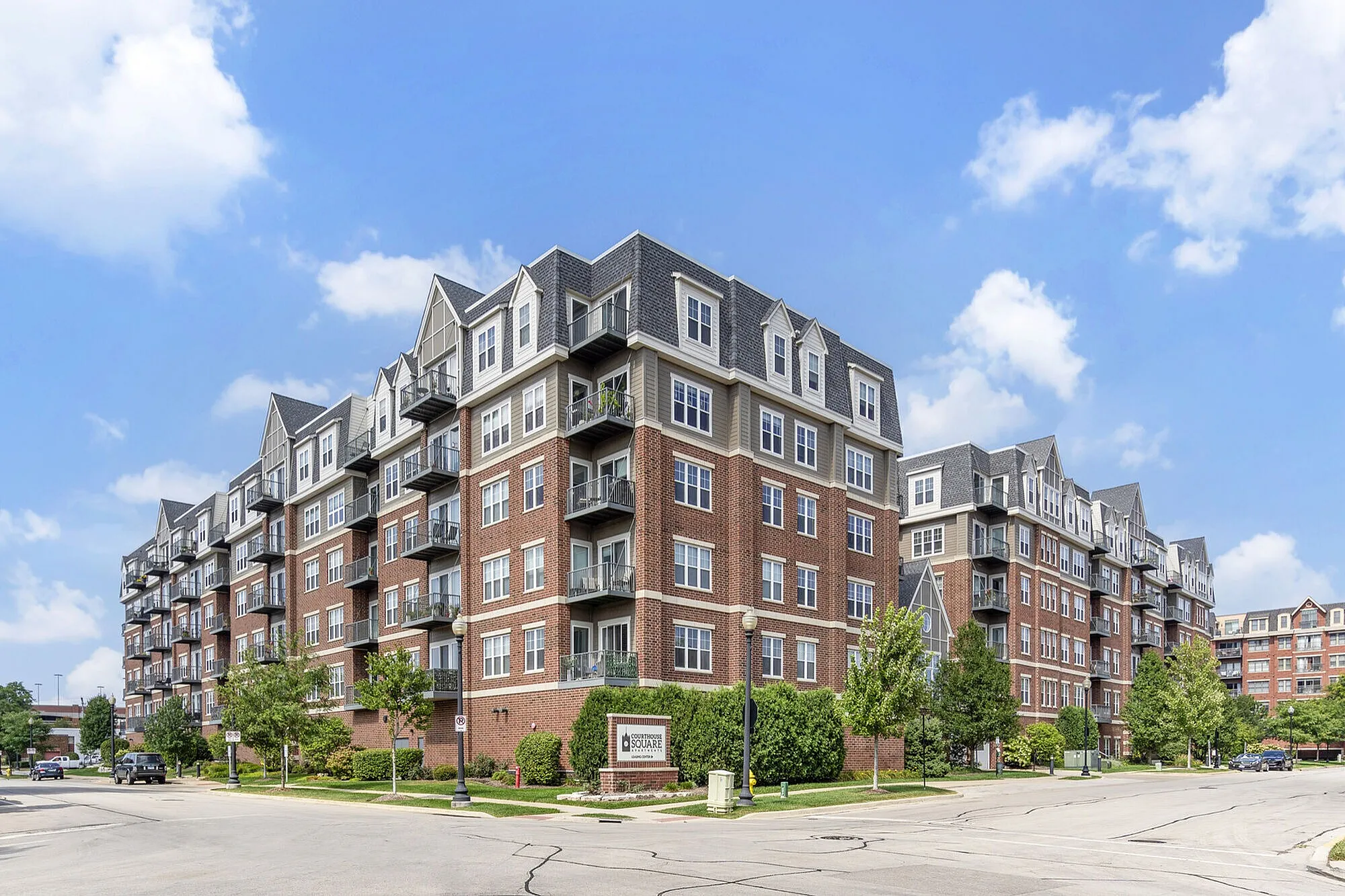 Elegant brick apartment complex with modern balconies and beautifully landscaped surroundings in a vibrant neighborhood.