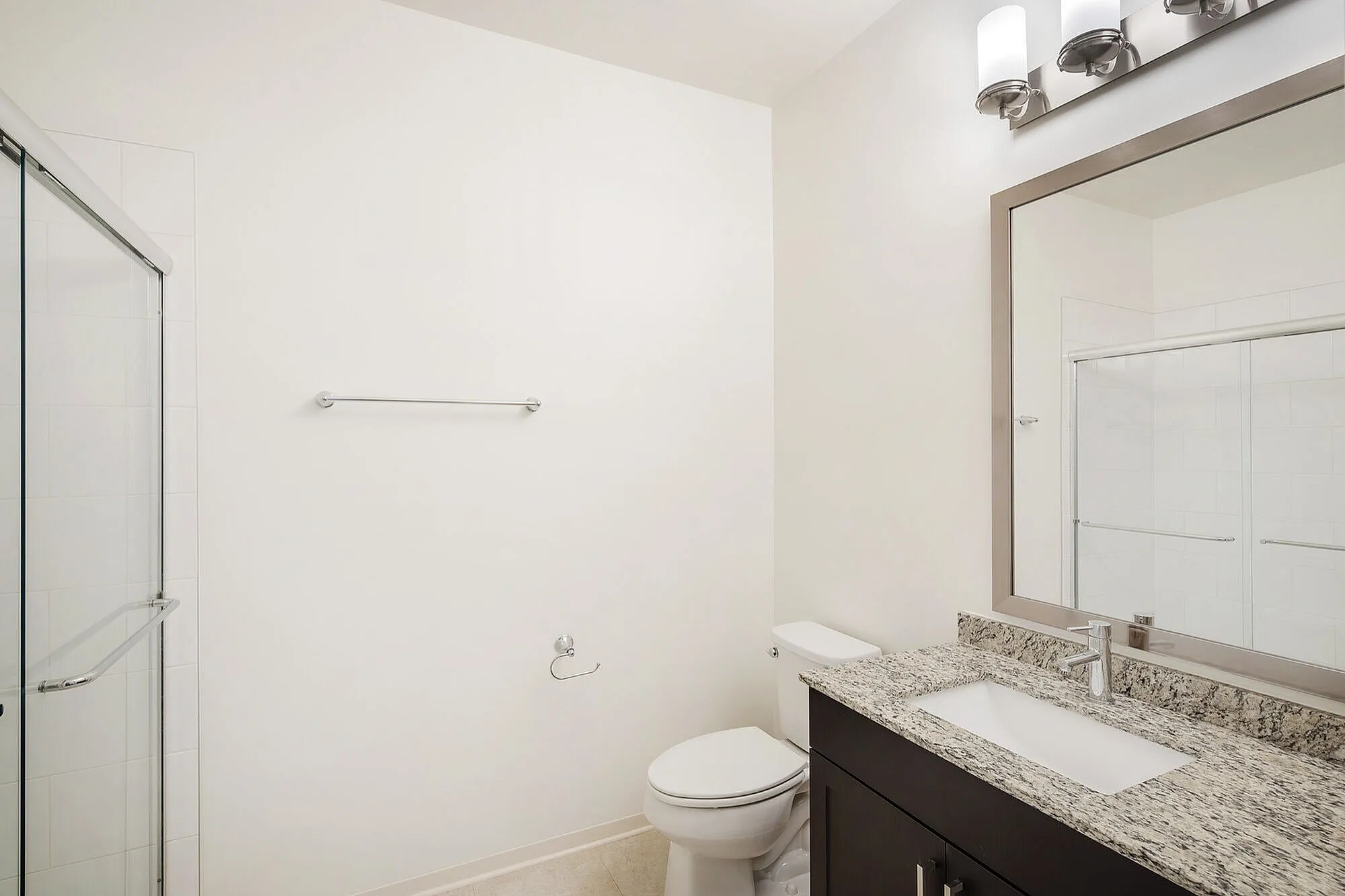 Modern bathroom with elegant granite countertop, sleek fixtures, and a spacious glass shower.
