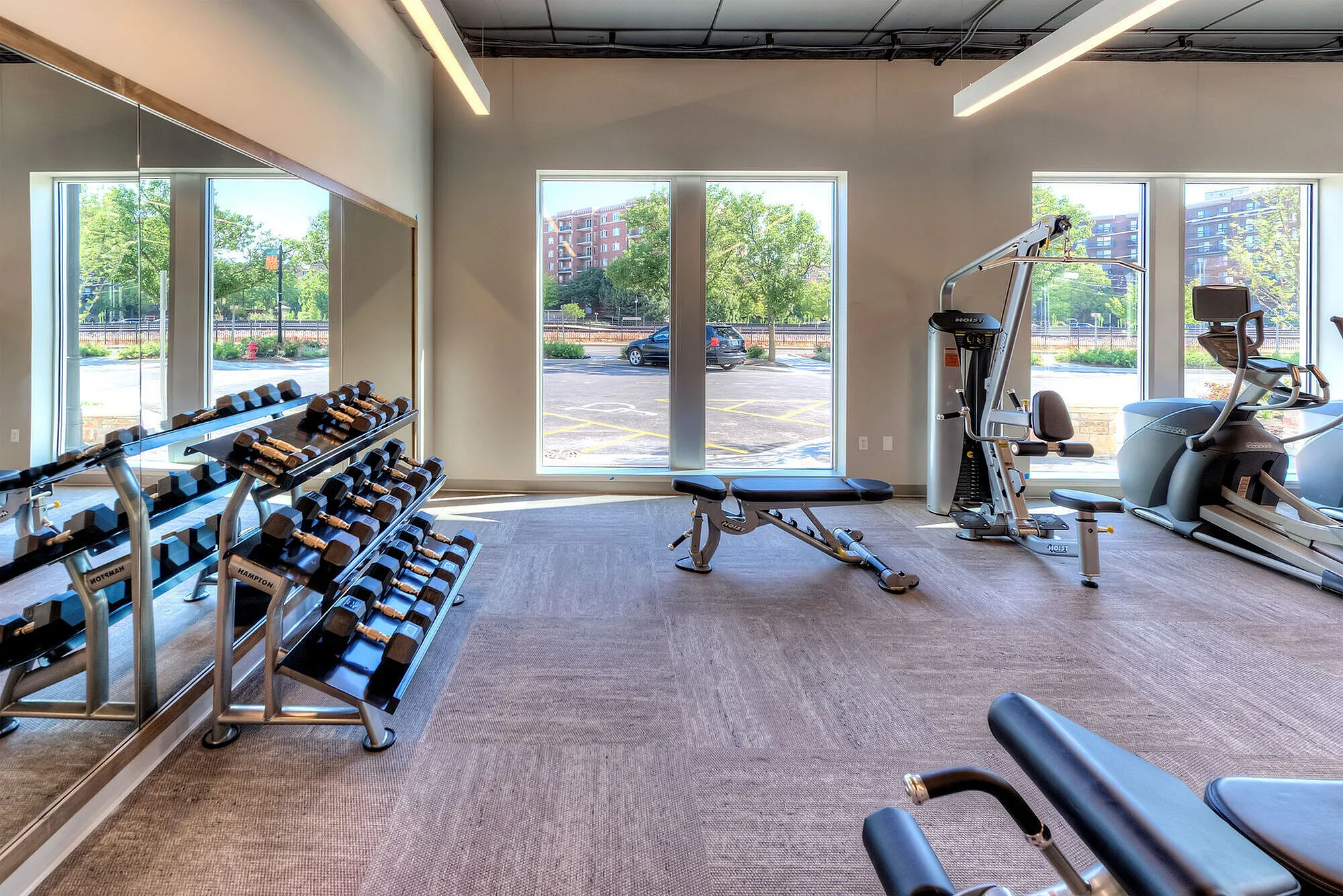 Bright and modern fitness center with state-of-the-art gym equipment, large windows, and sleek design.